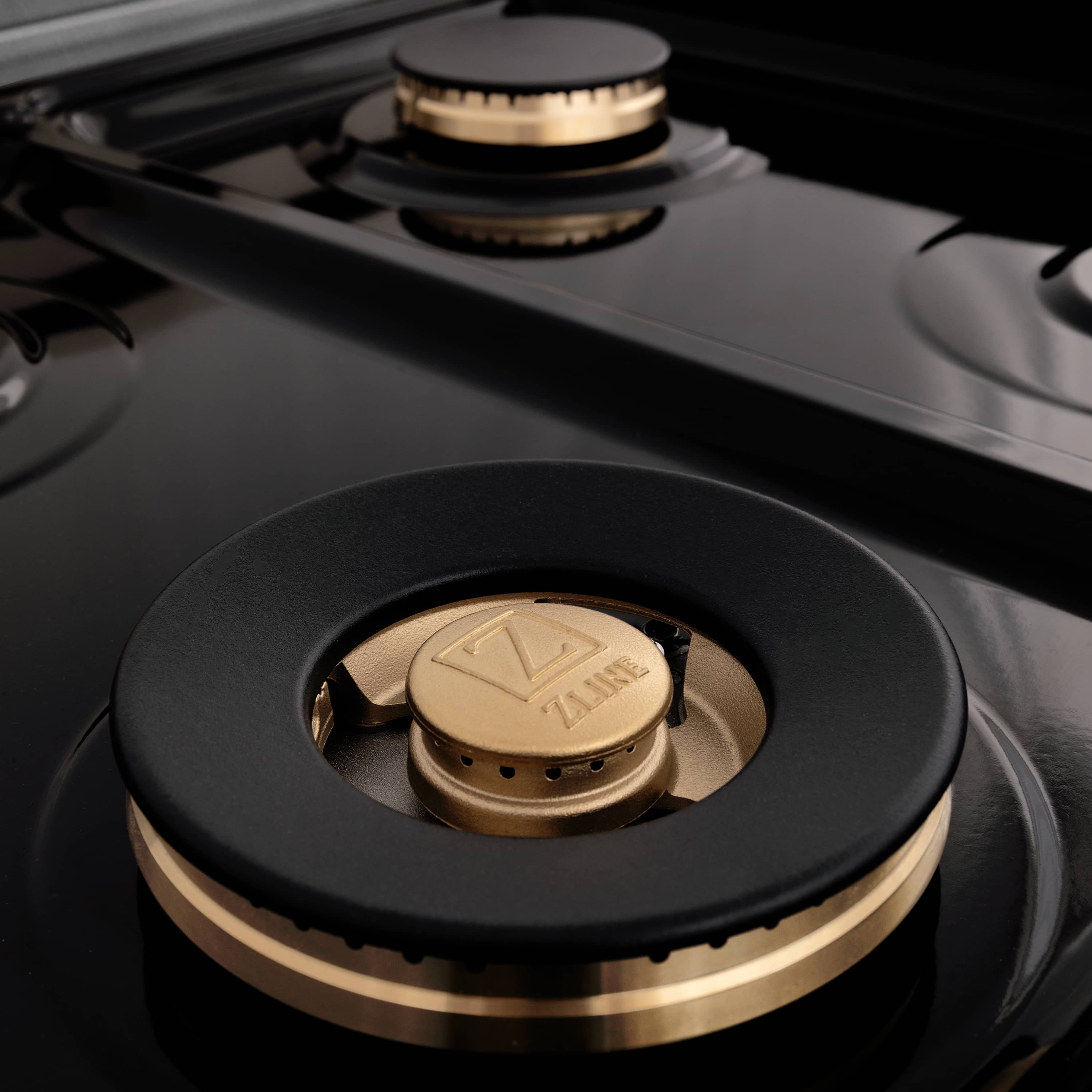 Black gas cooktop burner with round brass cap and metal burner ring