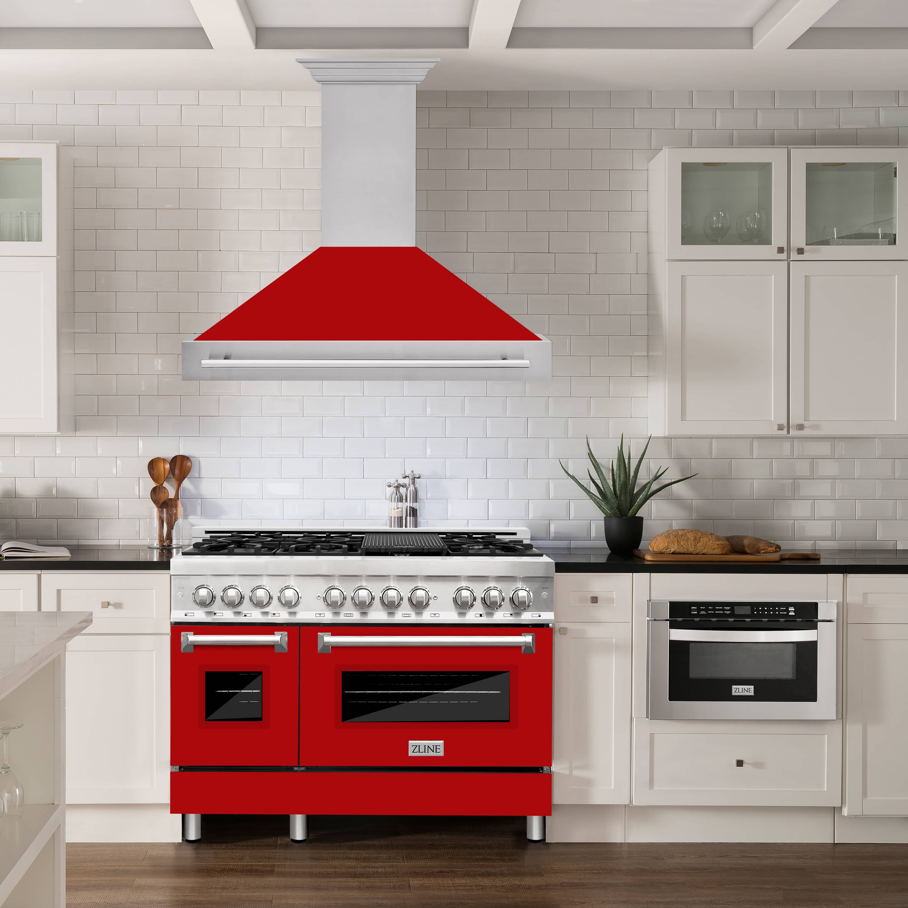 Wall mount range hood with red matte canopy and stainless handle above the cooktop