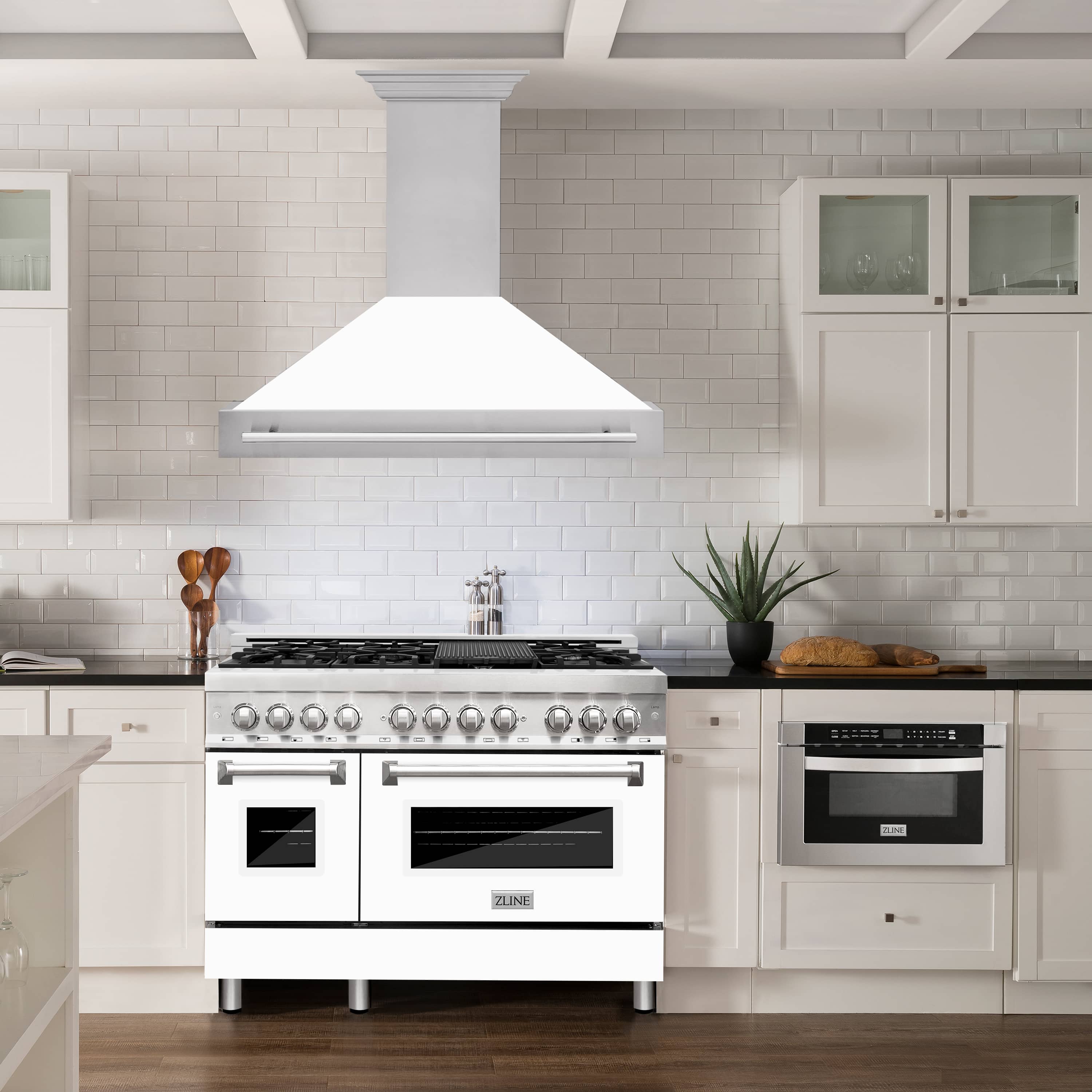 White matte wall mount range hood with stainless handle over a cooking range
