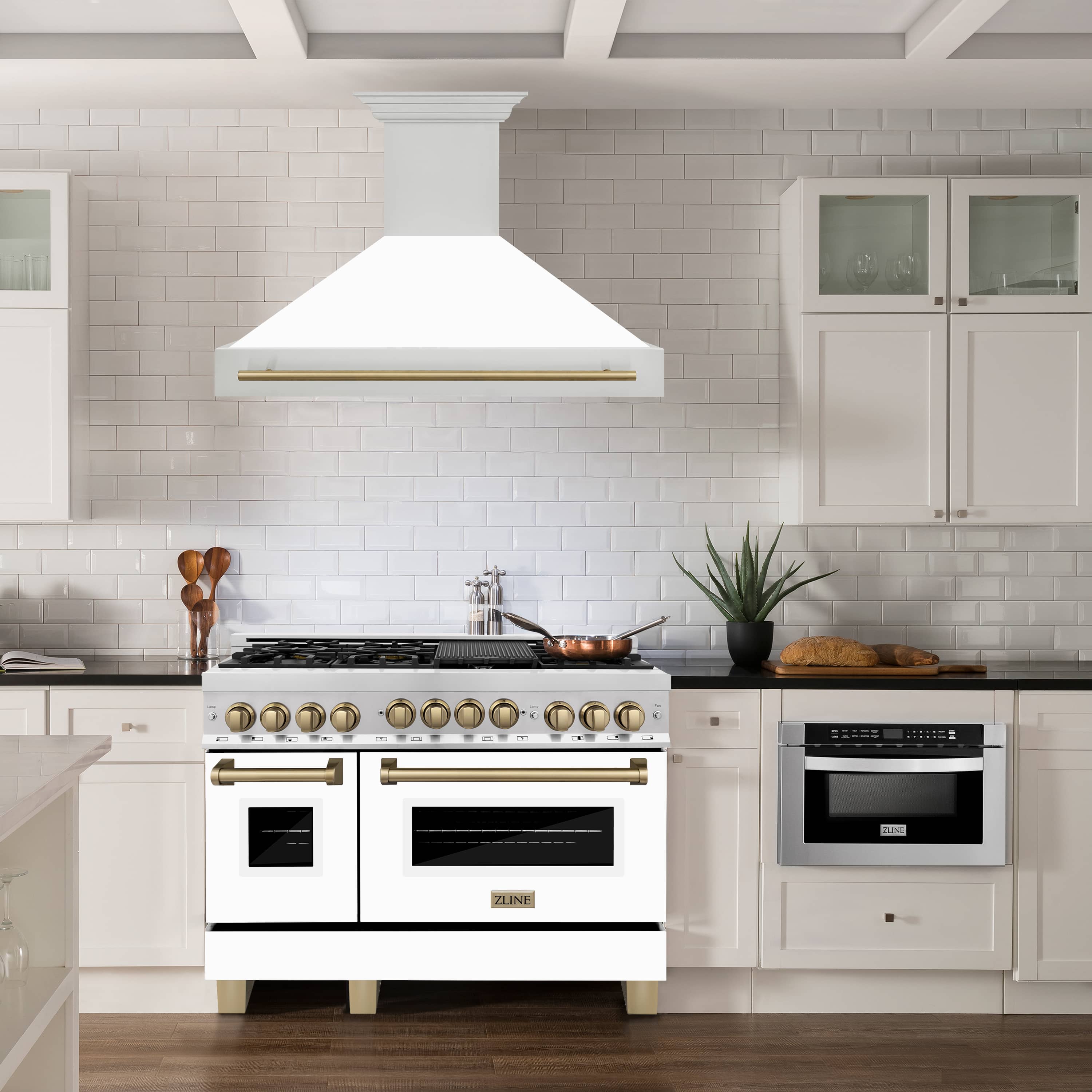 Stainless wall range hood with white matte chimney and champagne bronze handle over stove