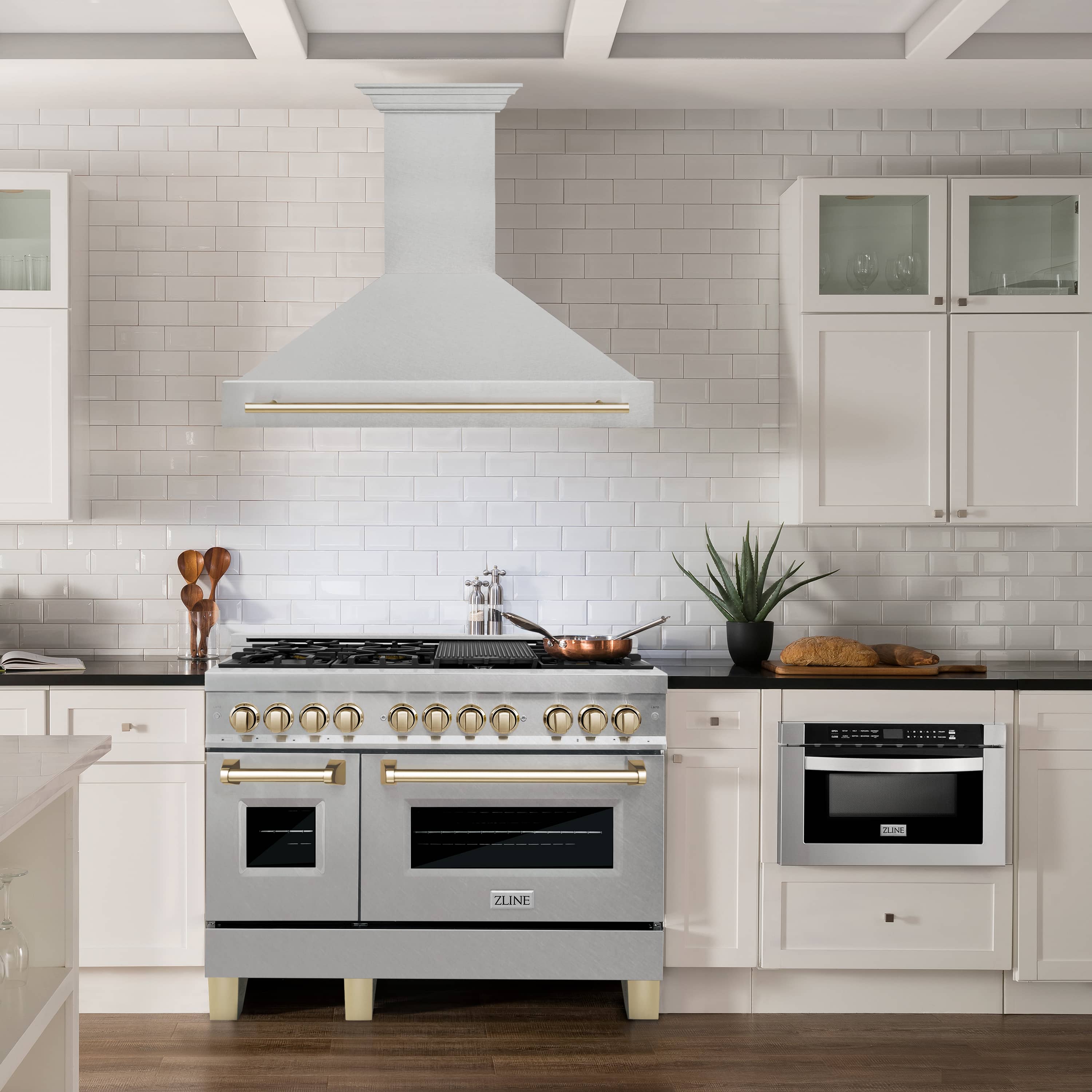 Stainless steel wall range hood with gold trim above a gas range in a kitchen