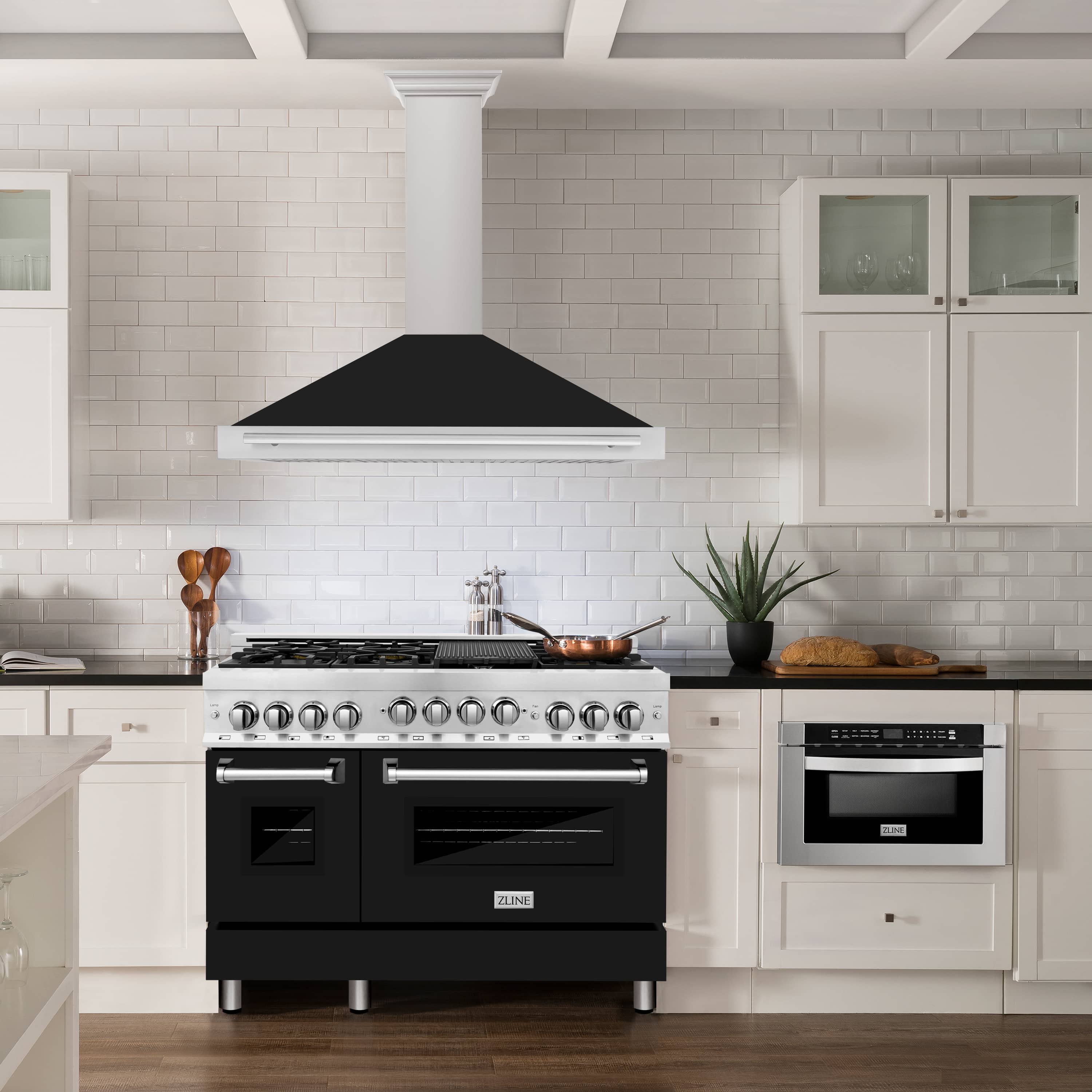 Wall-mounted range hood over cooktop; satin stainless chimney and black matte canopy