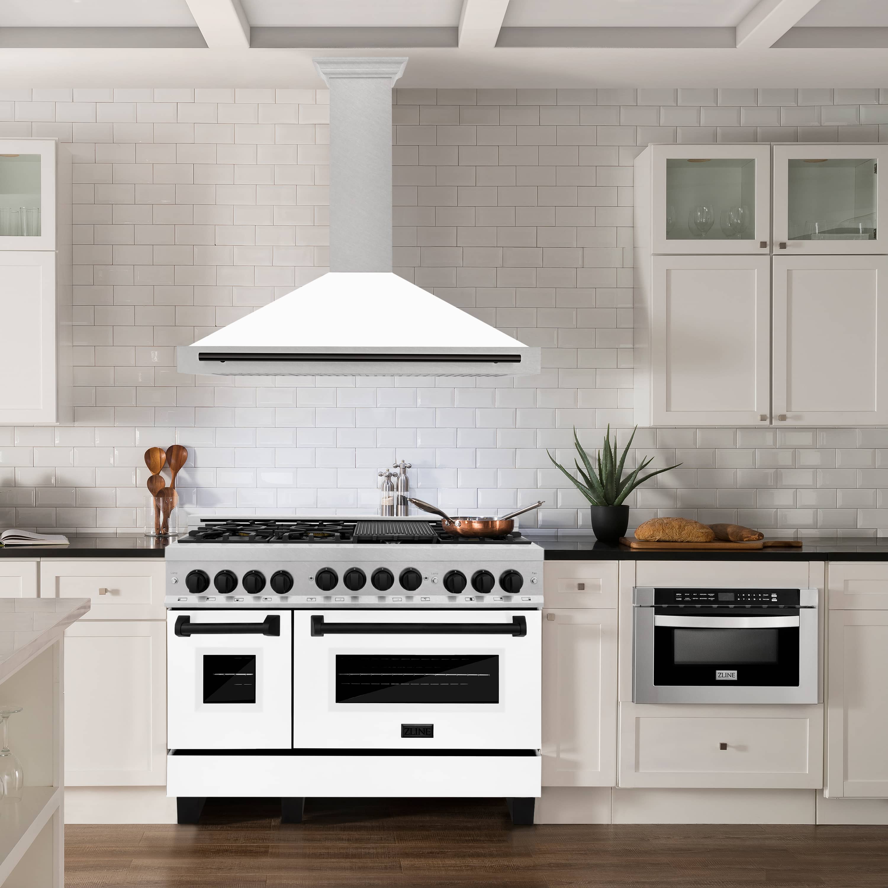 Wall mounted range hood over range with white tile backsplash and matte black accents