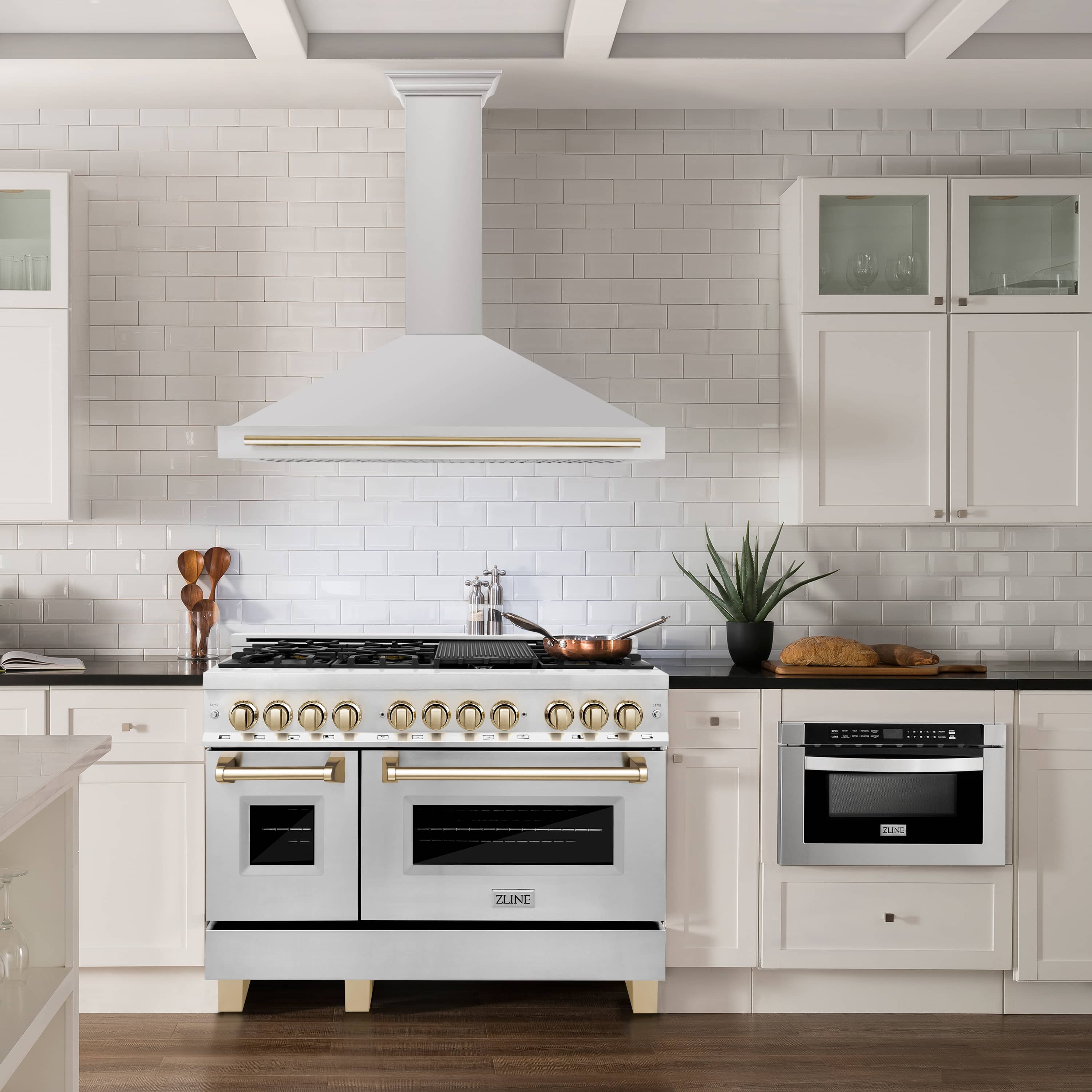 Wall-mounted range hood above stove with white chimney and gold trim strip