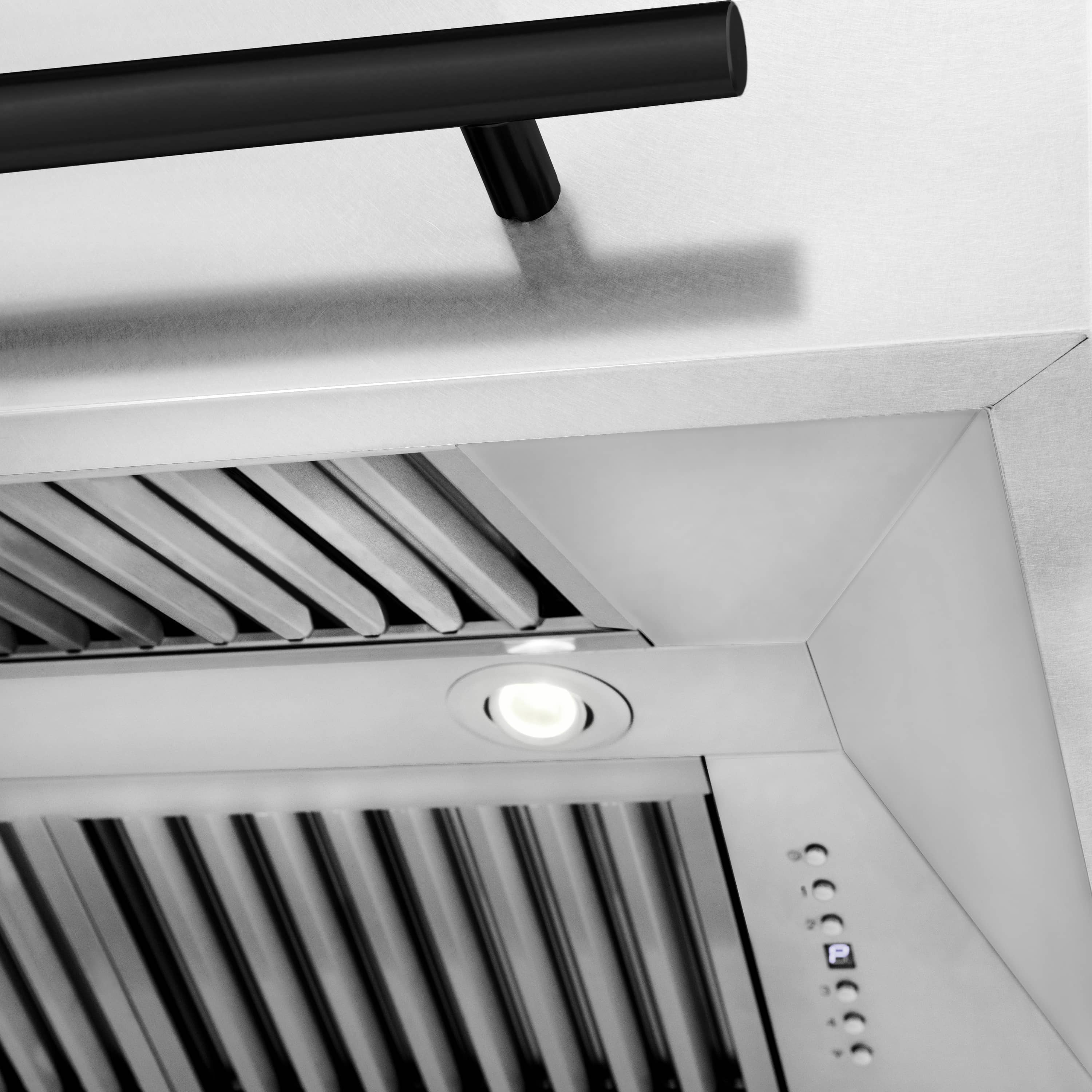 Range hood vent area with black handle bar, stainless filters, and round light