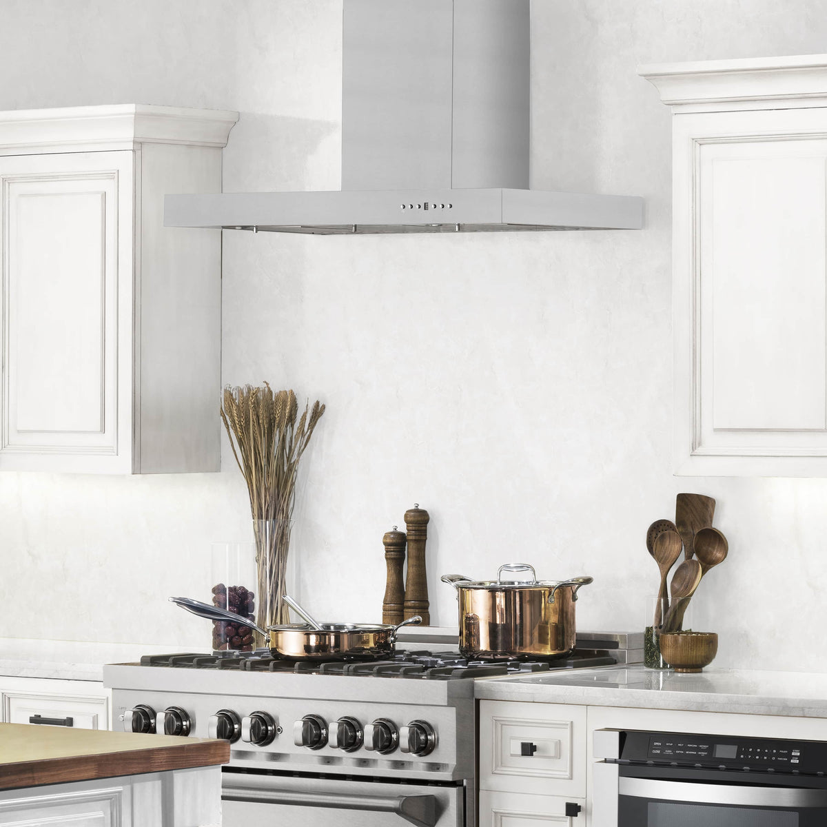 Stainless steel wall mount range hood centered over a stovetop in a bright kitchen