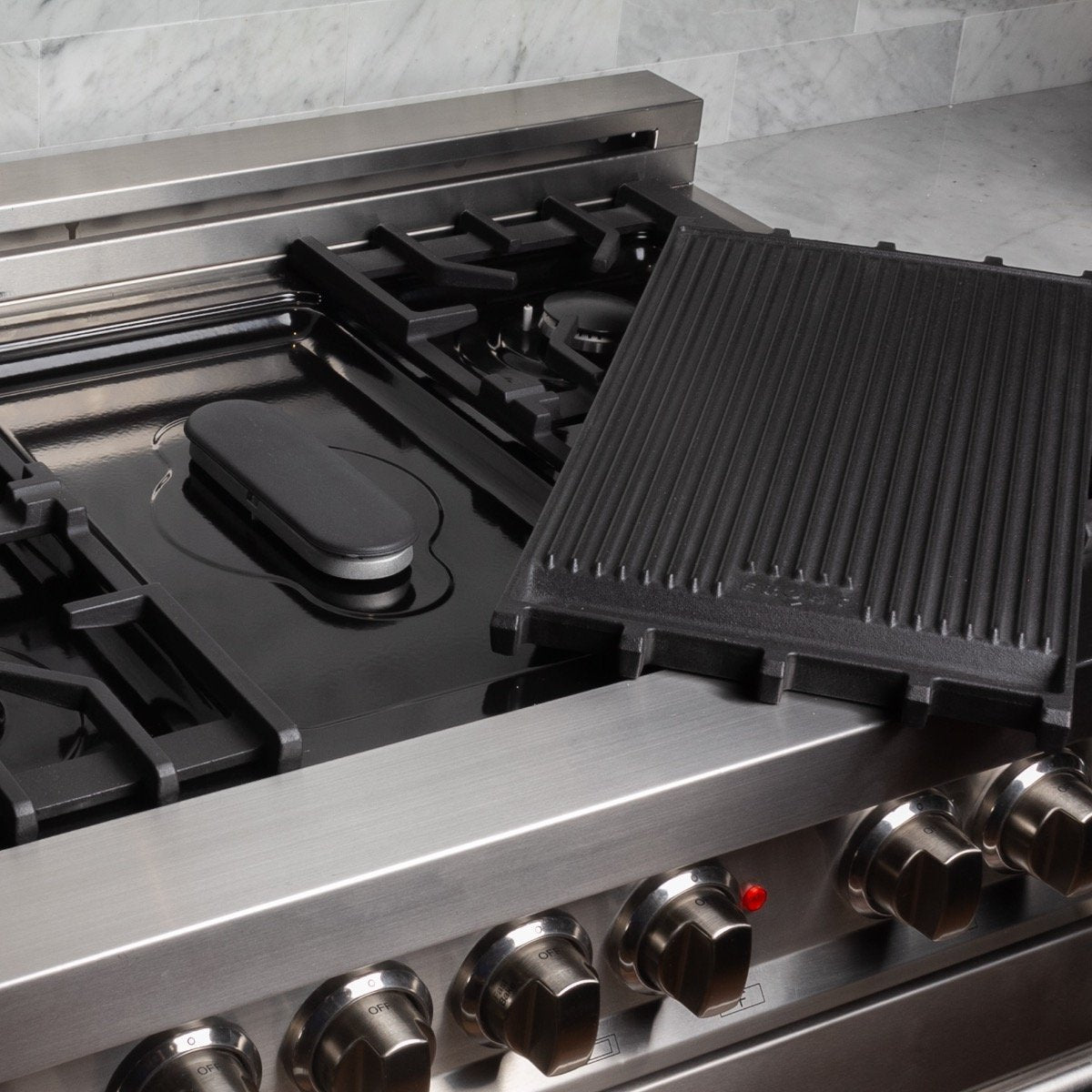 Stainless steel gas cooktop with black grates and single burner cap