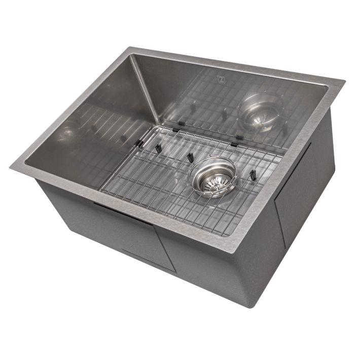 Single-bowl stainless steel kitchen sink with bottom grid and drain strainer.