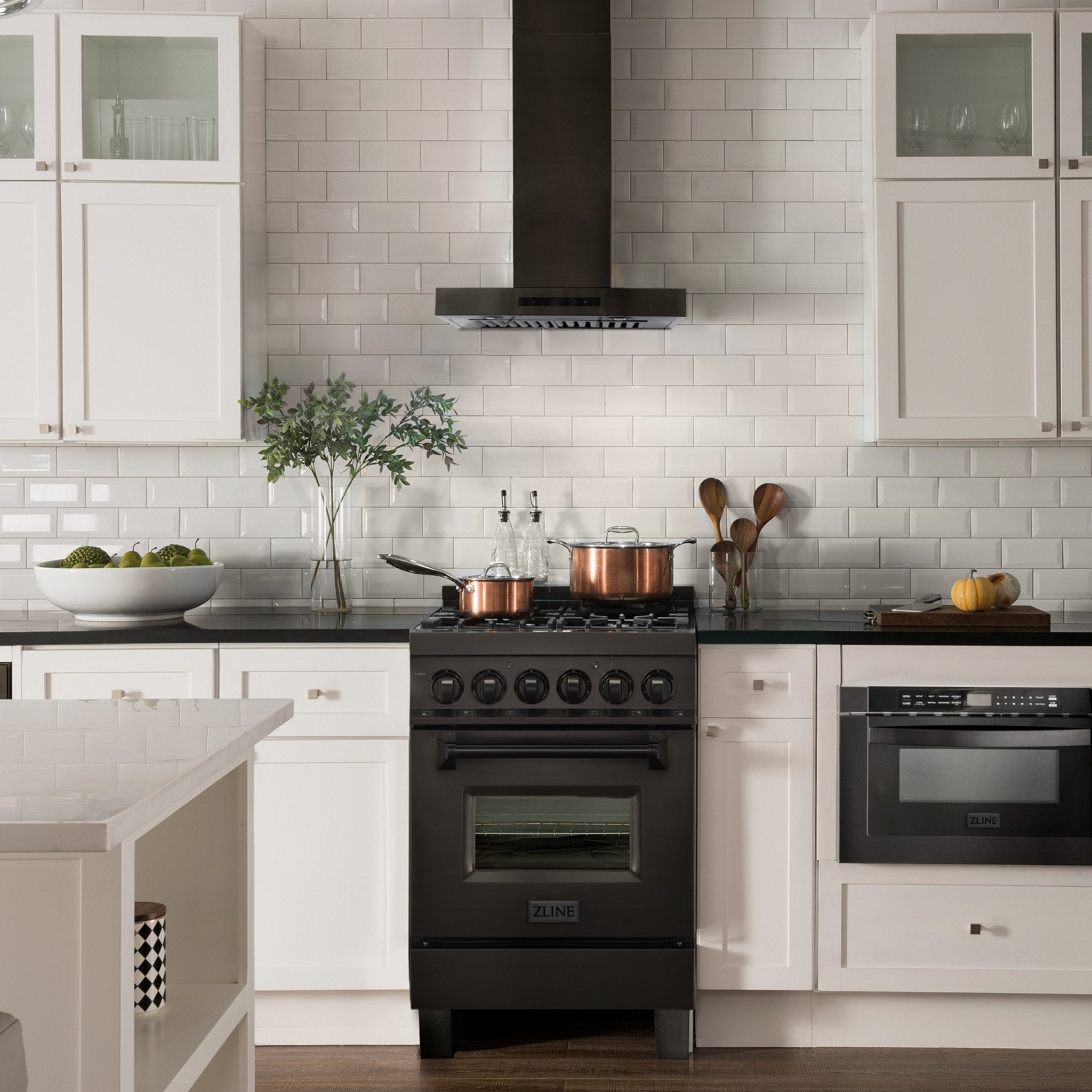 Black stainless steel wall-mount range hood centered above a gas range in a white kitchen