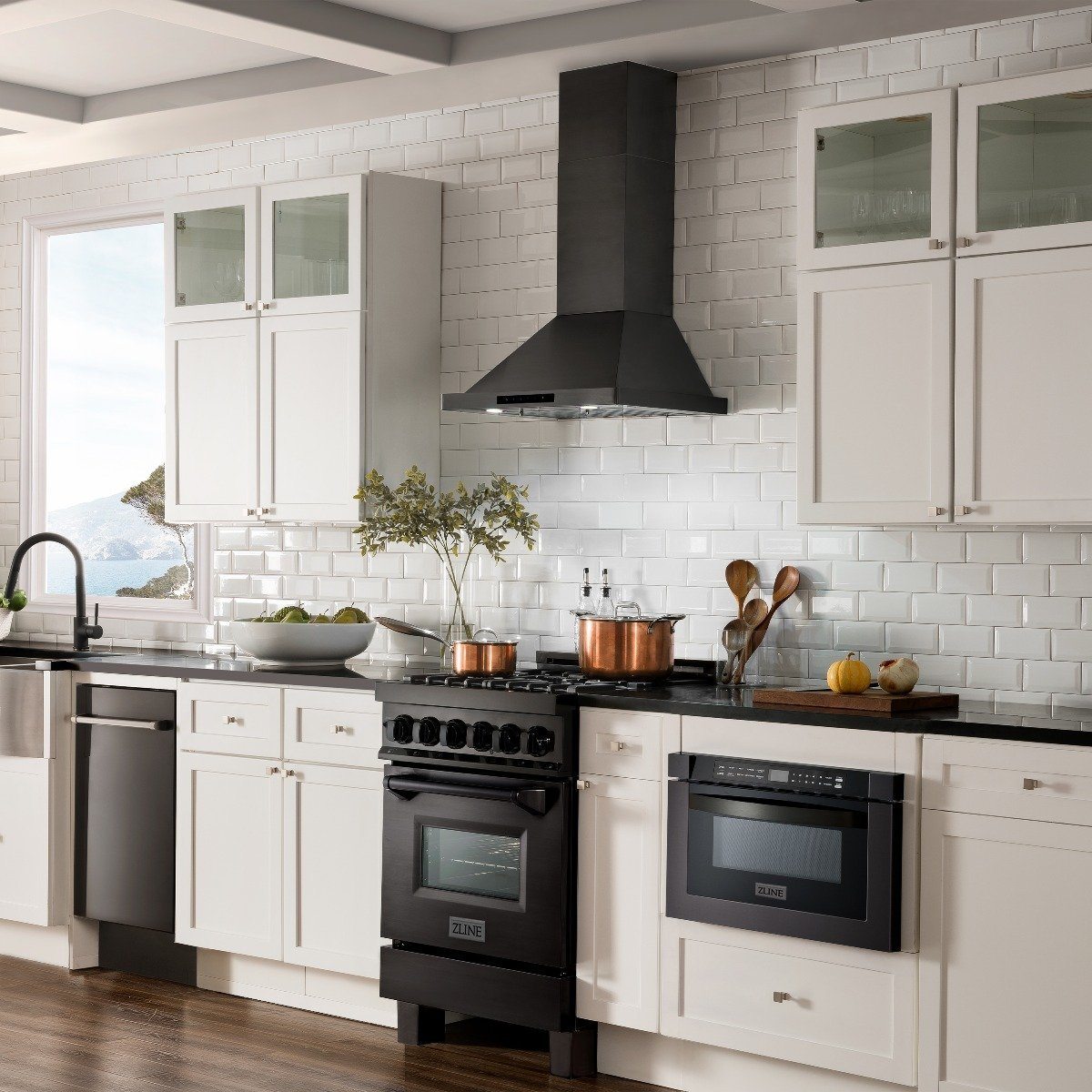 Black wall mount range hood centered over the stove in a white cabinet kitchen.