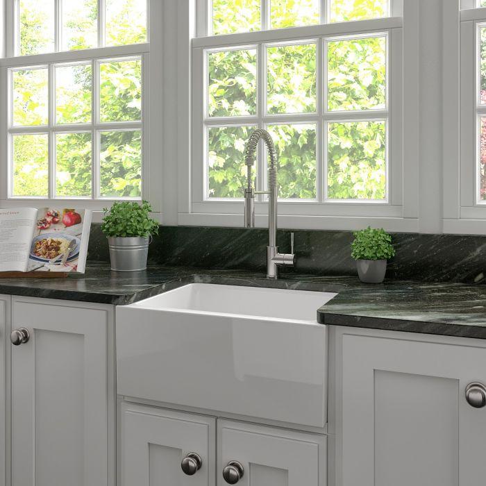 White farmhouse apron-front kitchen sink with single bowl and deck mount faucet