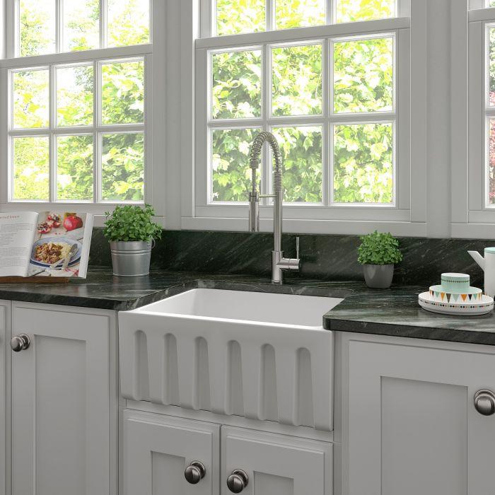 White matte apron-front farmhouse kitchen sink with single bowl and gooseneck faucet