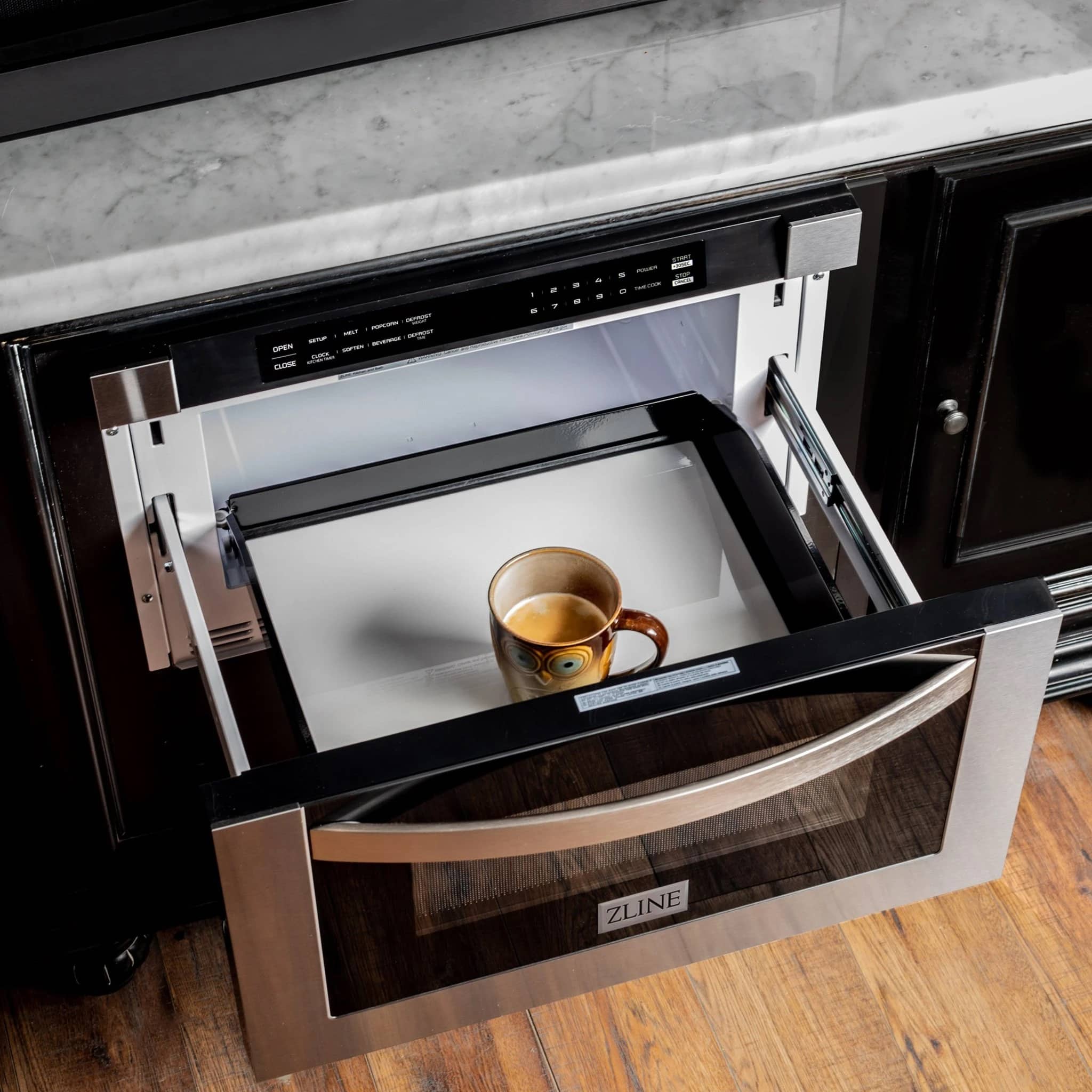 Black stainless microwave drawer open with a cup inside the cooking cavity