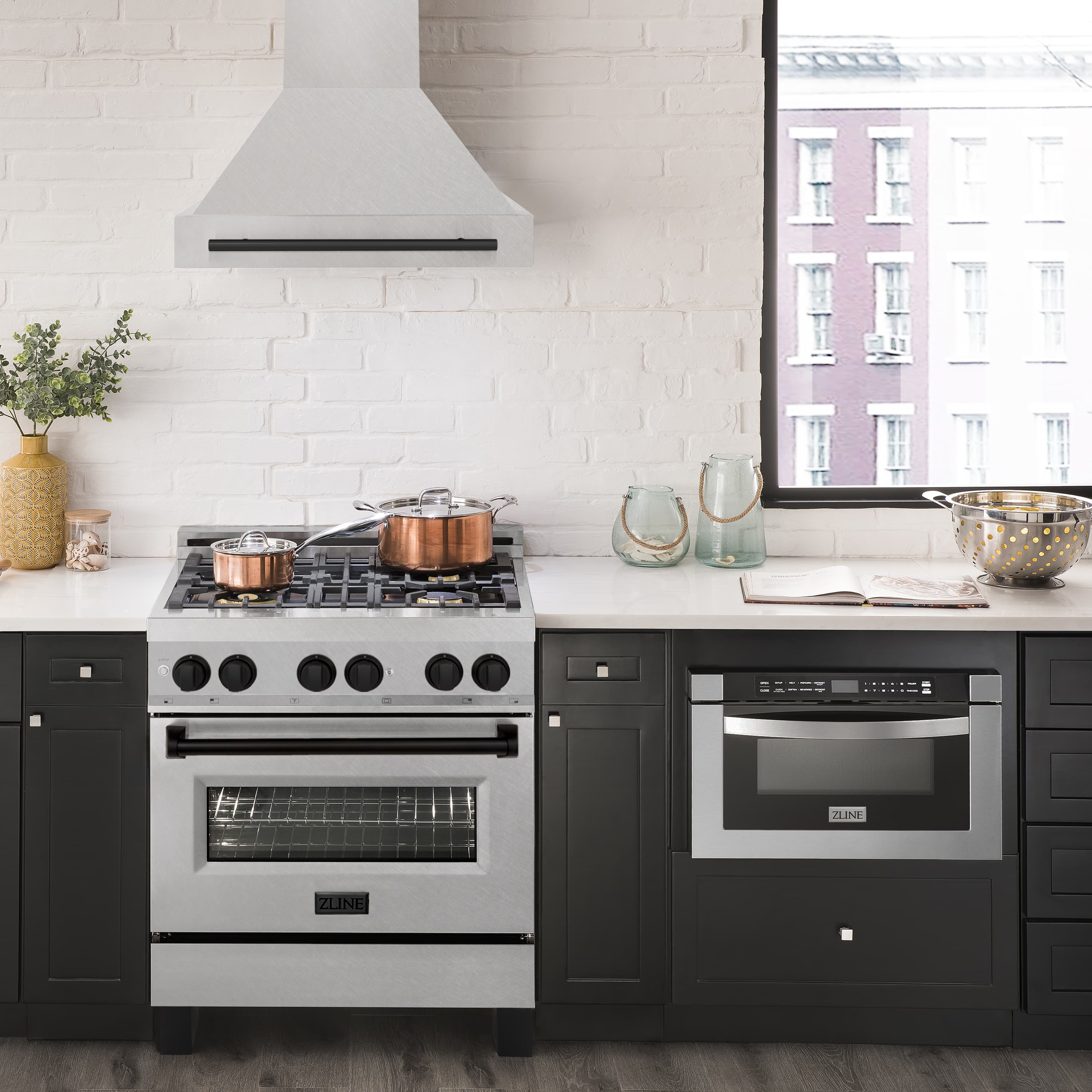 Wall mount range hood with satin stainless chimney and matte black handle above stove