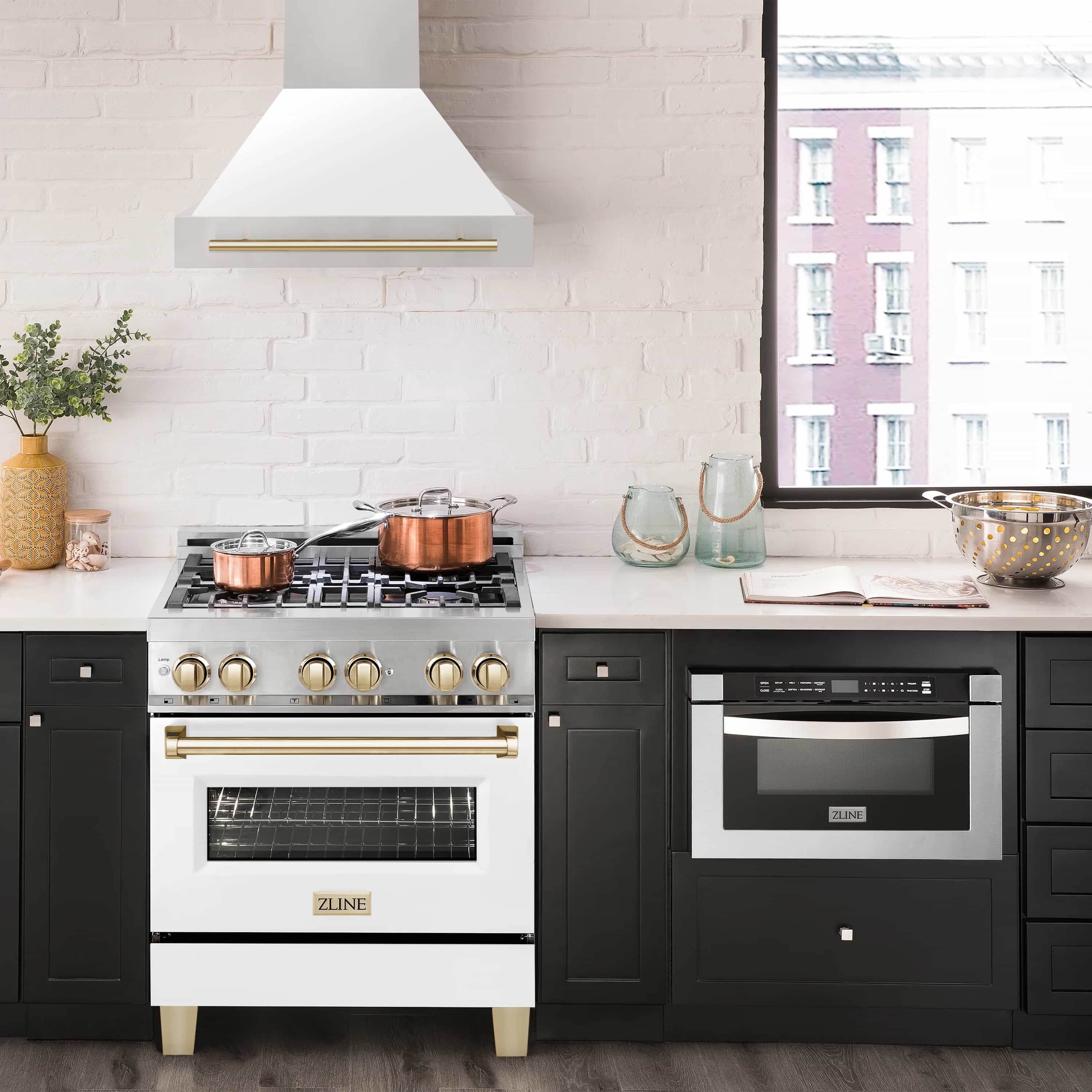 Wall mount range hood above stove, white matte chimney with gold trim and stainless hood body.