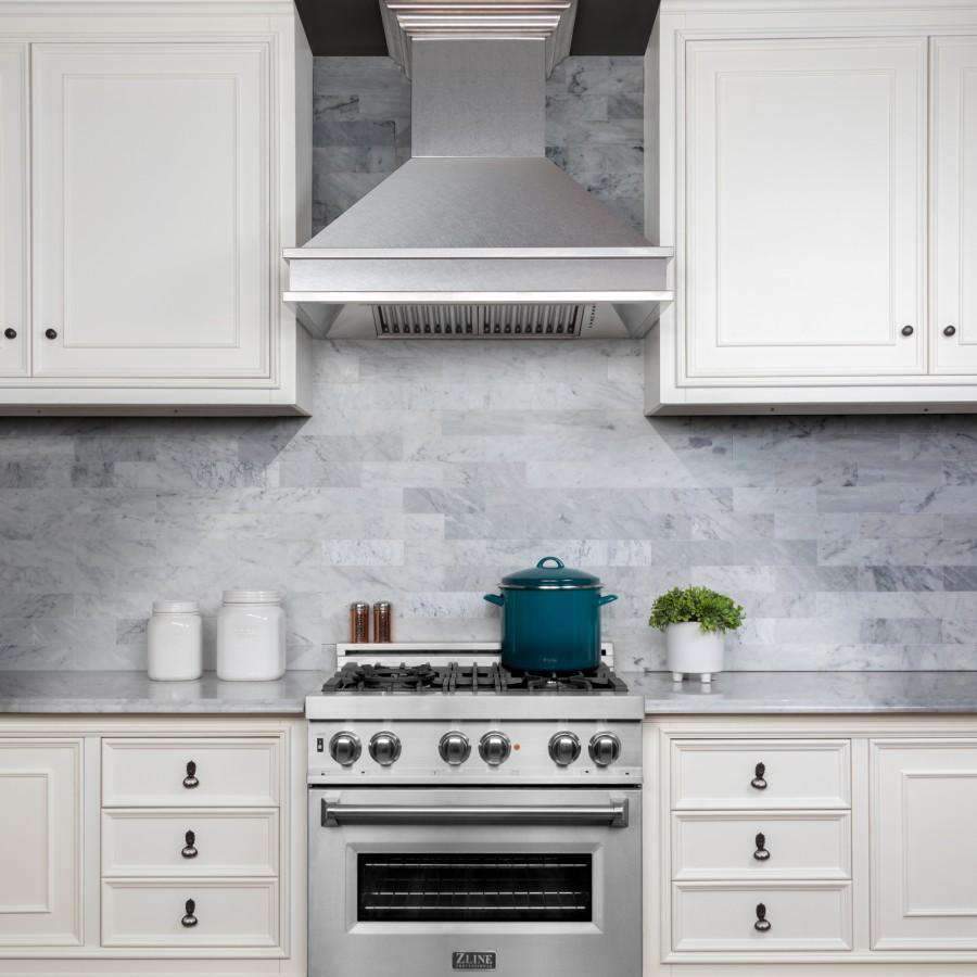 Wall mount range hood with stainless chimney and vent grille centered above stove.