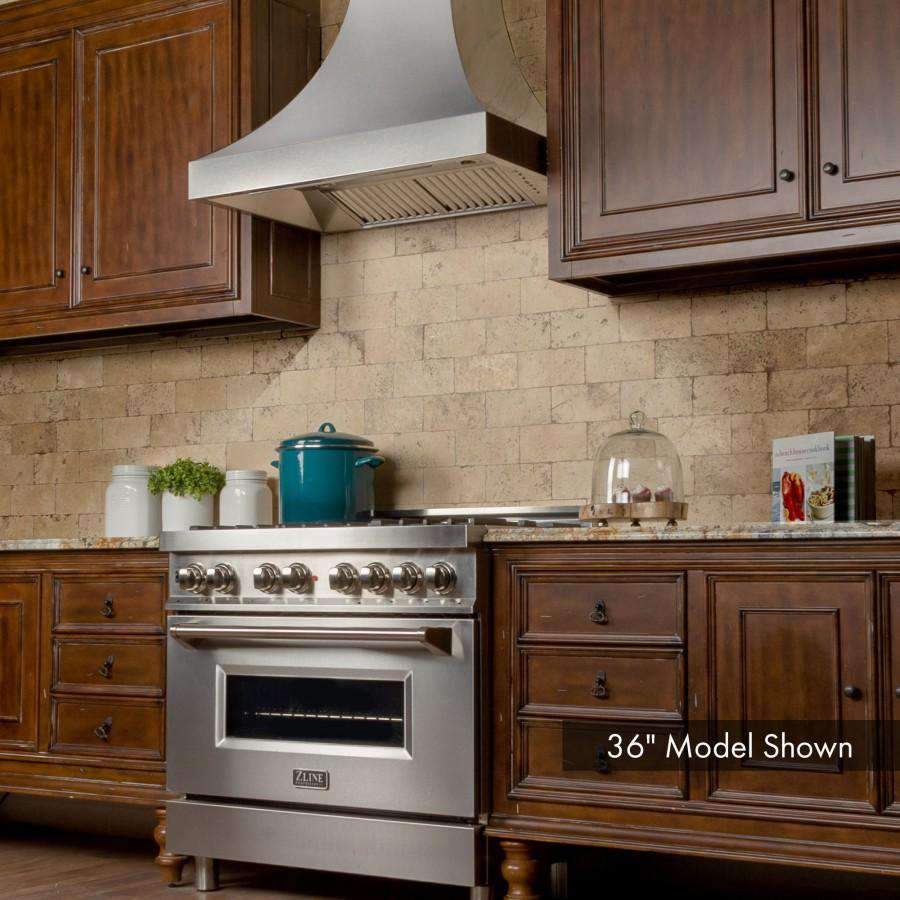 Wall-mounted stainless steel range hood above a gas range in wood cabinet kitchen