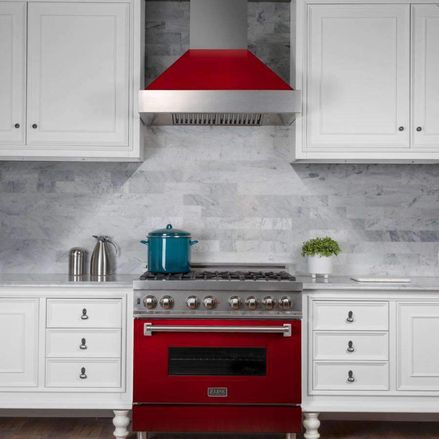 Stainless wall range hood with red gloss canopy above red gas range, vented grille visible.