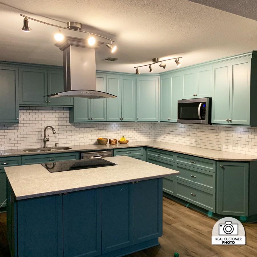 Stainless steel island range hood above a kitchen cooktop in a cabinet-lined space