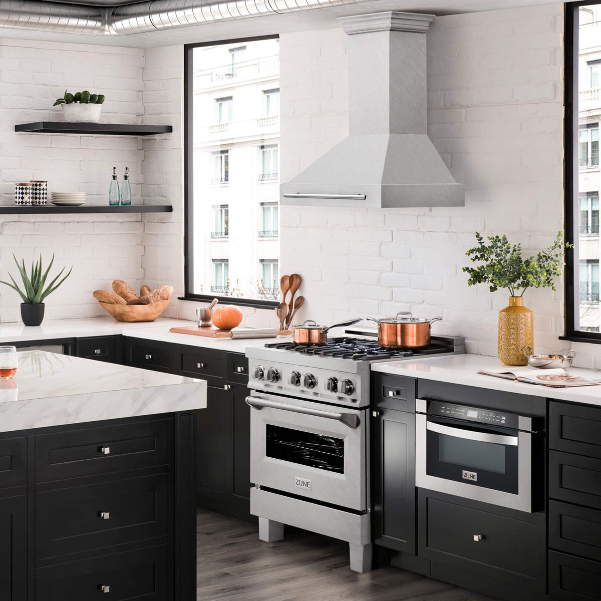 Wall mount satin stainless steel range hood above a kitchen cooktop, with chimney and handle bar