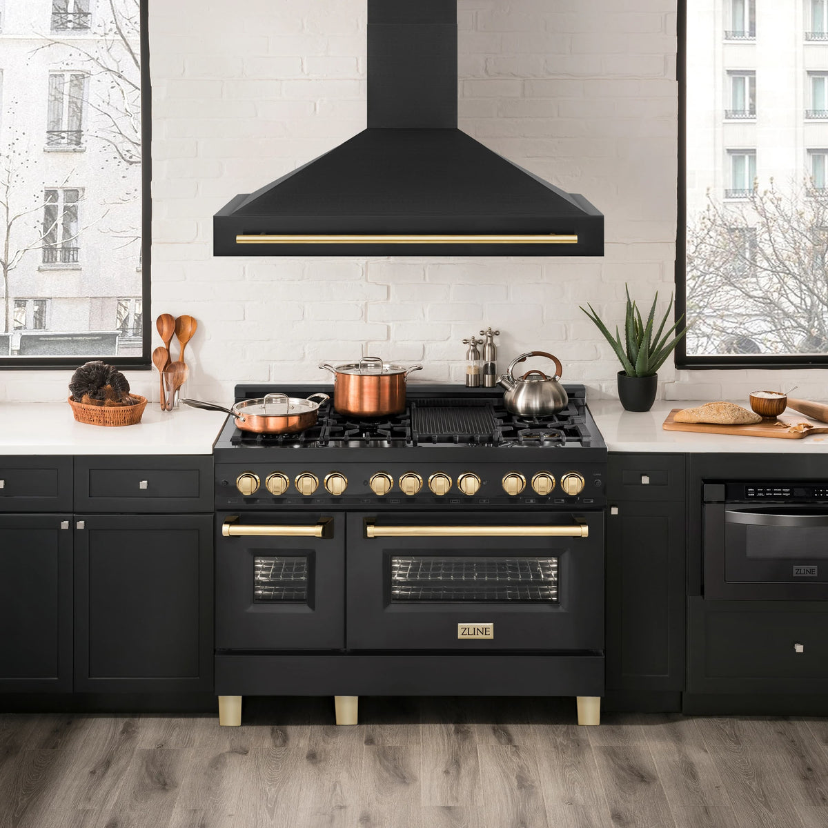 Black chimney-style wall-mount range hood with gold trim above cooktop