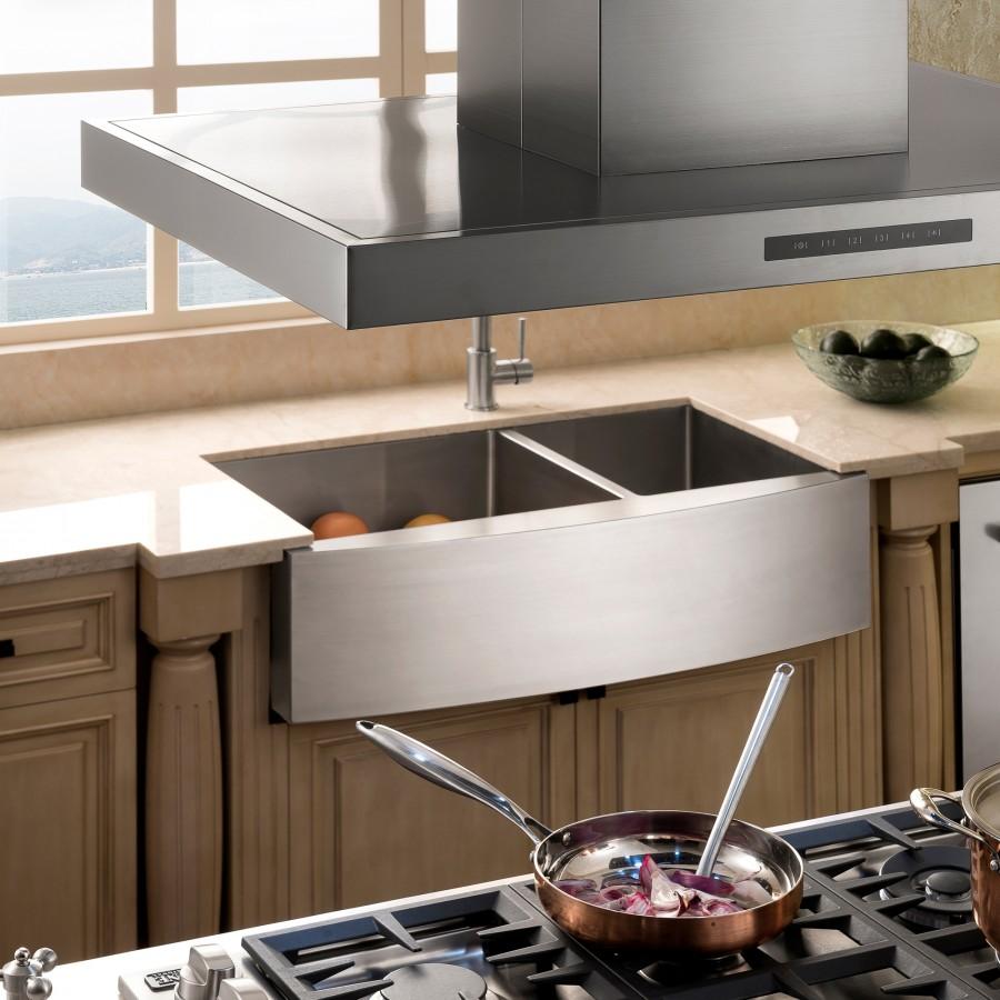 Apron-mounted stainless steel double-basin sink with faucet over left basin.