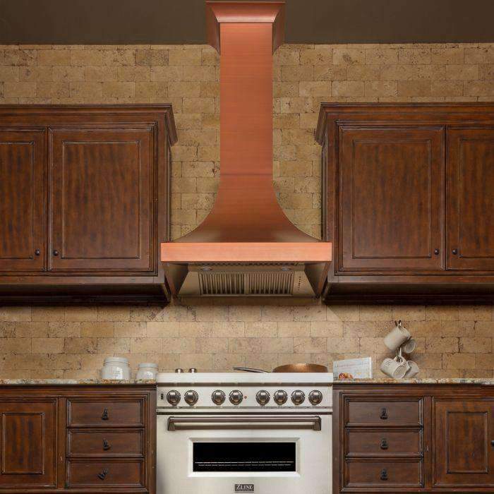 Copper-finish chimney wall range hood above cooktop