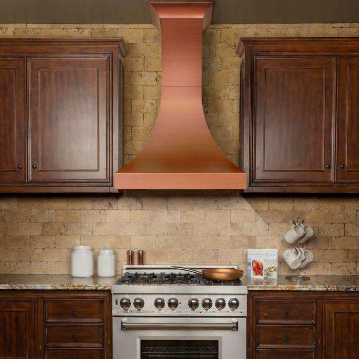 Copper-finish wall chimney range hood centered between cabinets