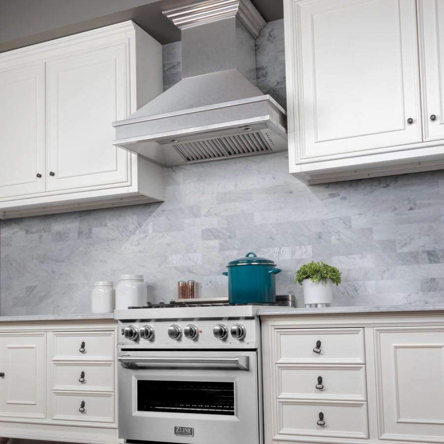 Satin stainless steel wall mount range hood over a gas range in a kitchen