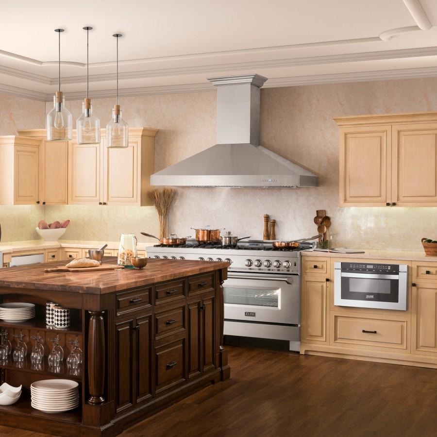 Stainless steel ducted wall mount range hood above a stove in a warmly lit kitchen