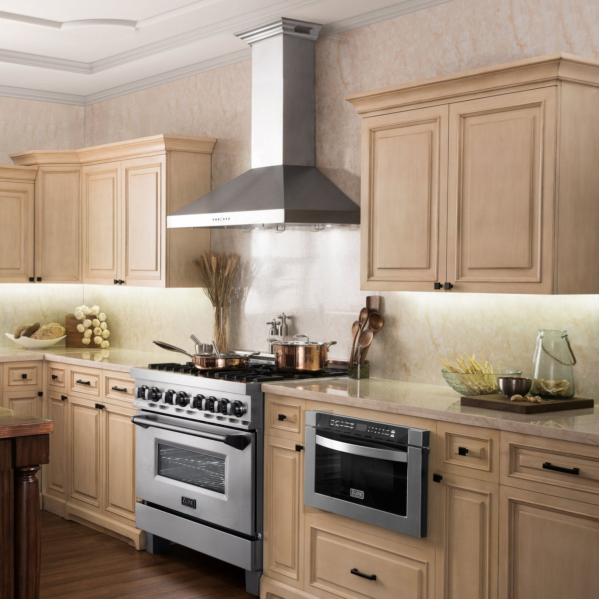 Stainless steel wall mount range hood centered above a kitchen stove in a cabinet surround.