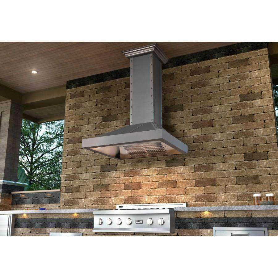 Stainless steel wall range hood mounted on stone exterior wall above cooktop