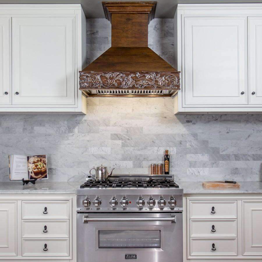 Wooden wall range hood with detailed crown molding over a stainless vent