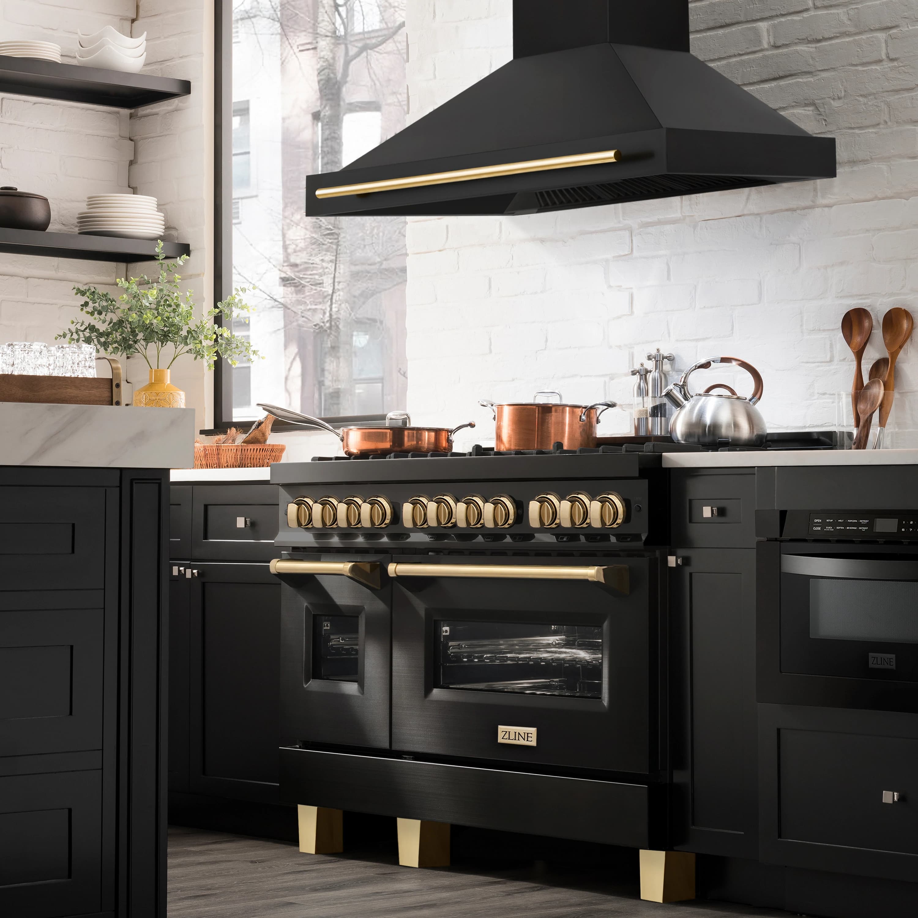 Black wall mount range hood with gold handle bar above kitchen cooktop