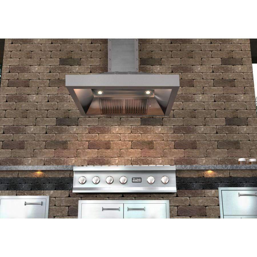 Stainless steel wall-mounted chimney range hood against stone outdoor kitchen wall