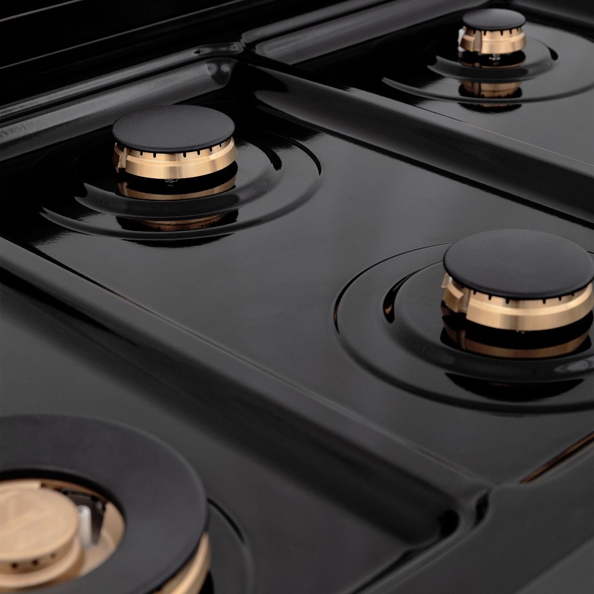 Black gas cooktop with four circular burners and gold-ring burner bases on grates