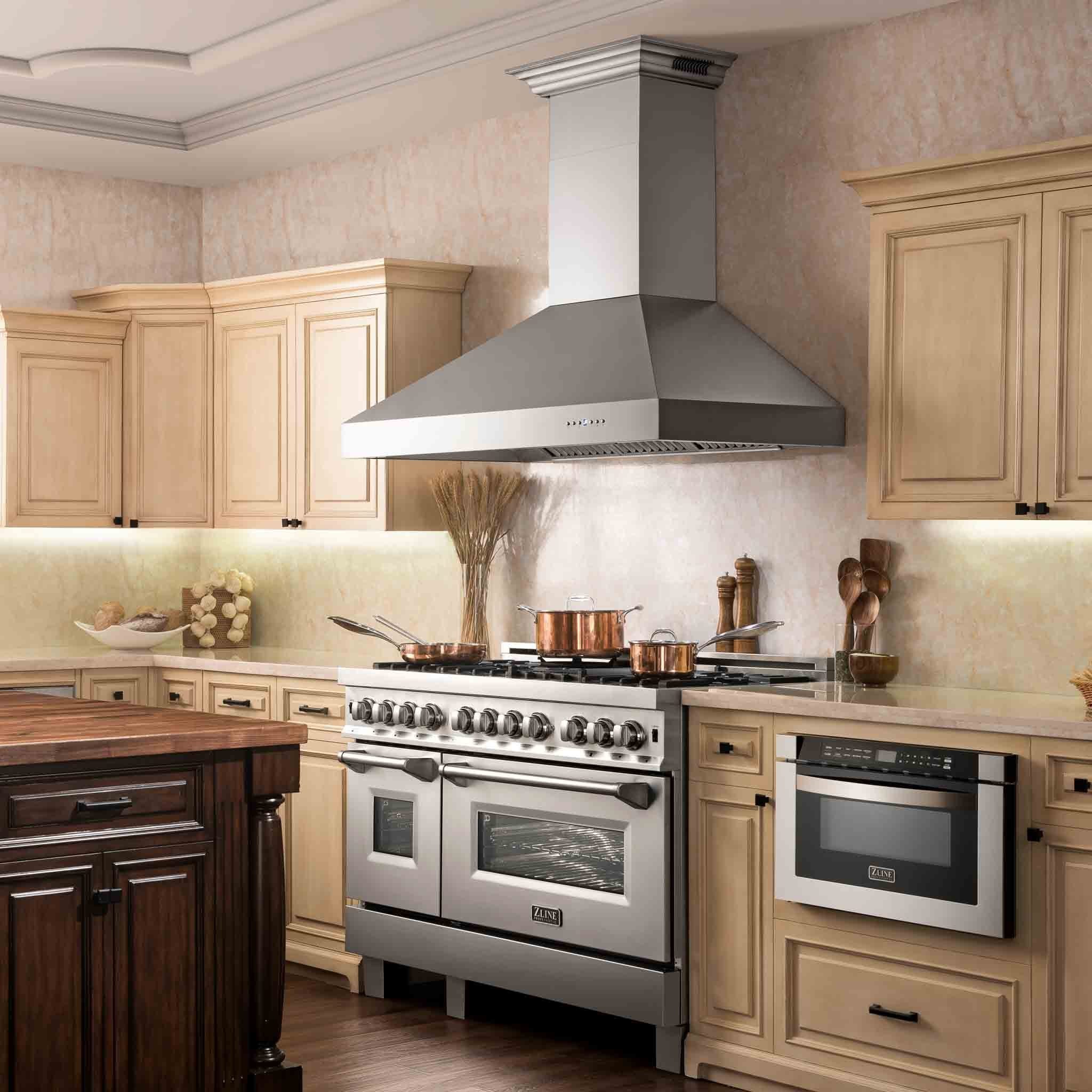 Stainless steel wall mount range hood above a kitchen cooktop on a cabinet wall
