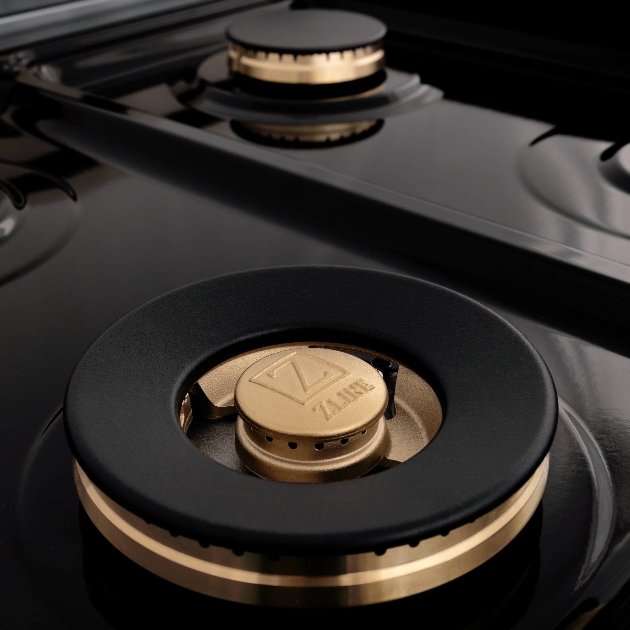 Gas cooktop burner with black grate and gold center cap