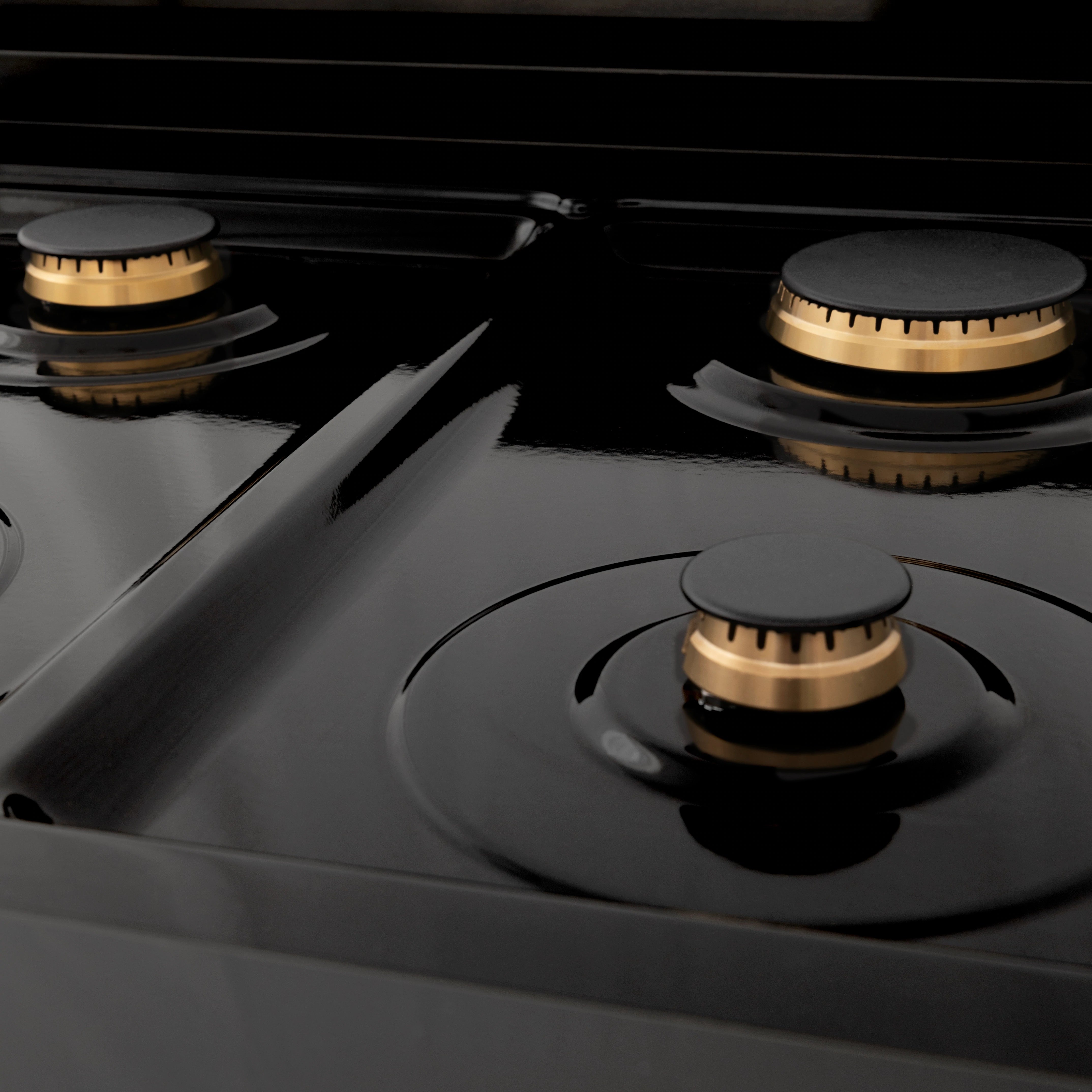 Black glass cooktop with three brass-tone burner caps and center knob