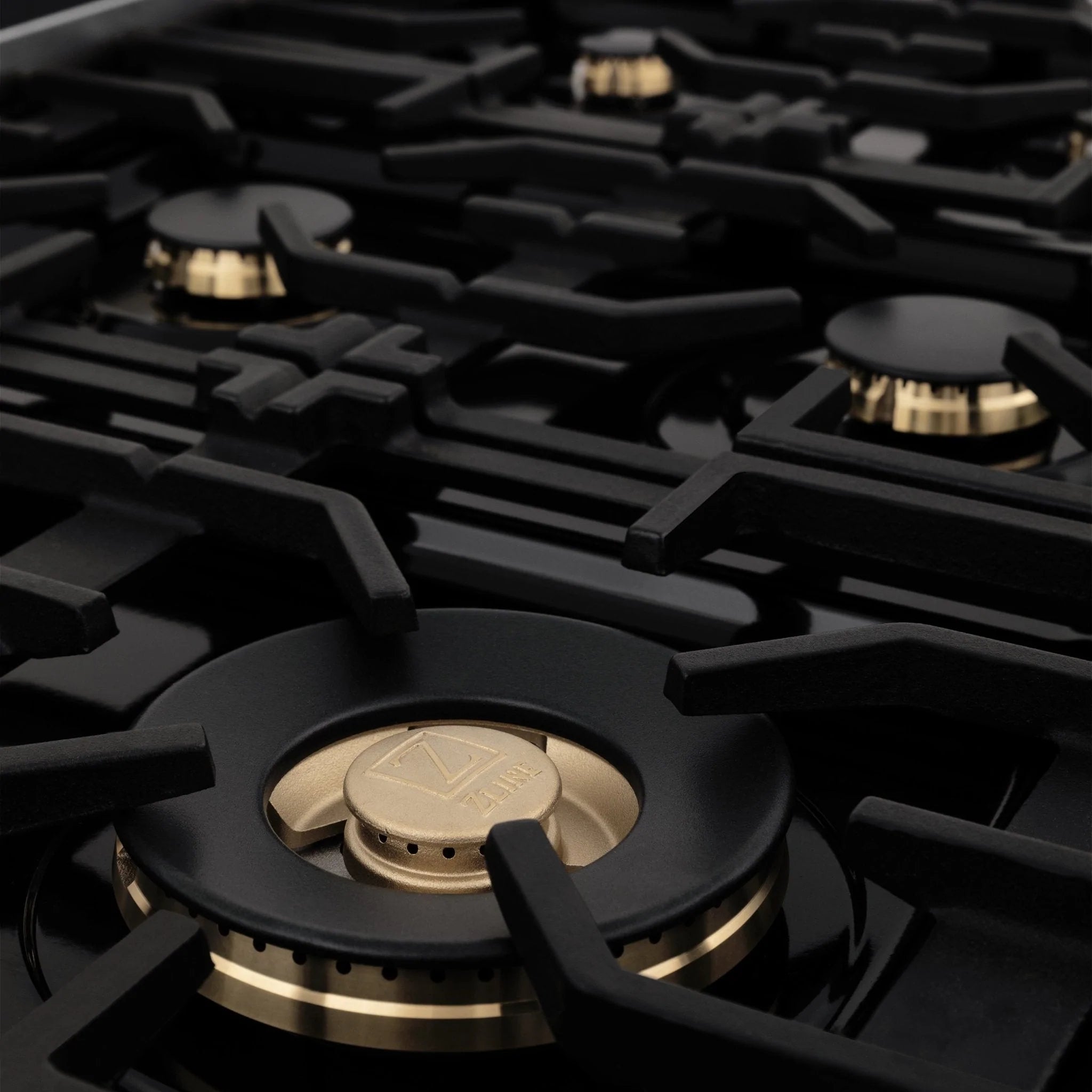Gold-accented gas burner with black grate on stainless range cooktop