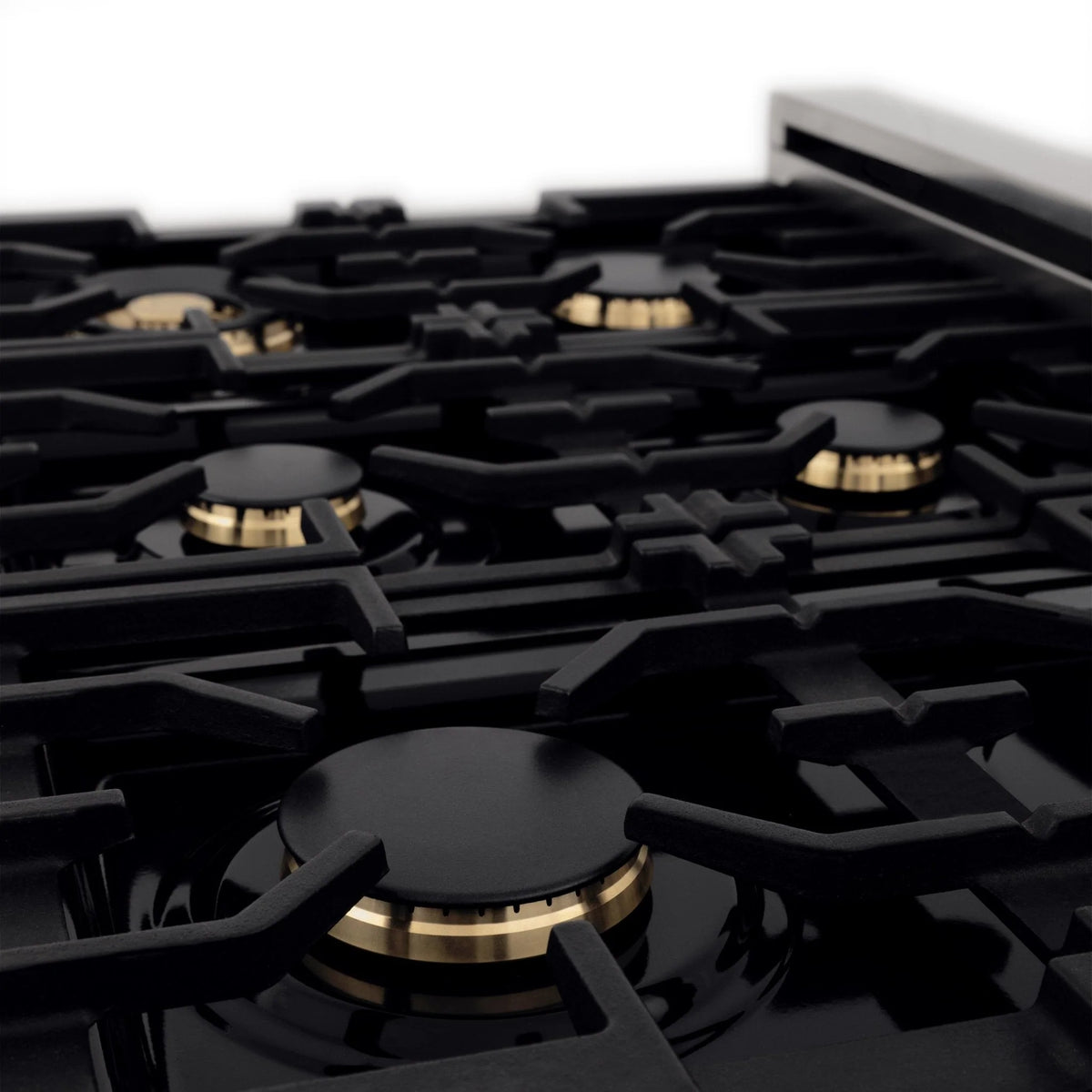 Black gas burners with brass-toned caps on a dual fuel range cooktop, close-up