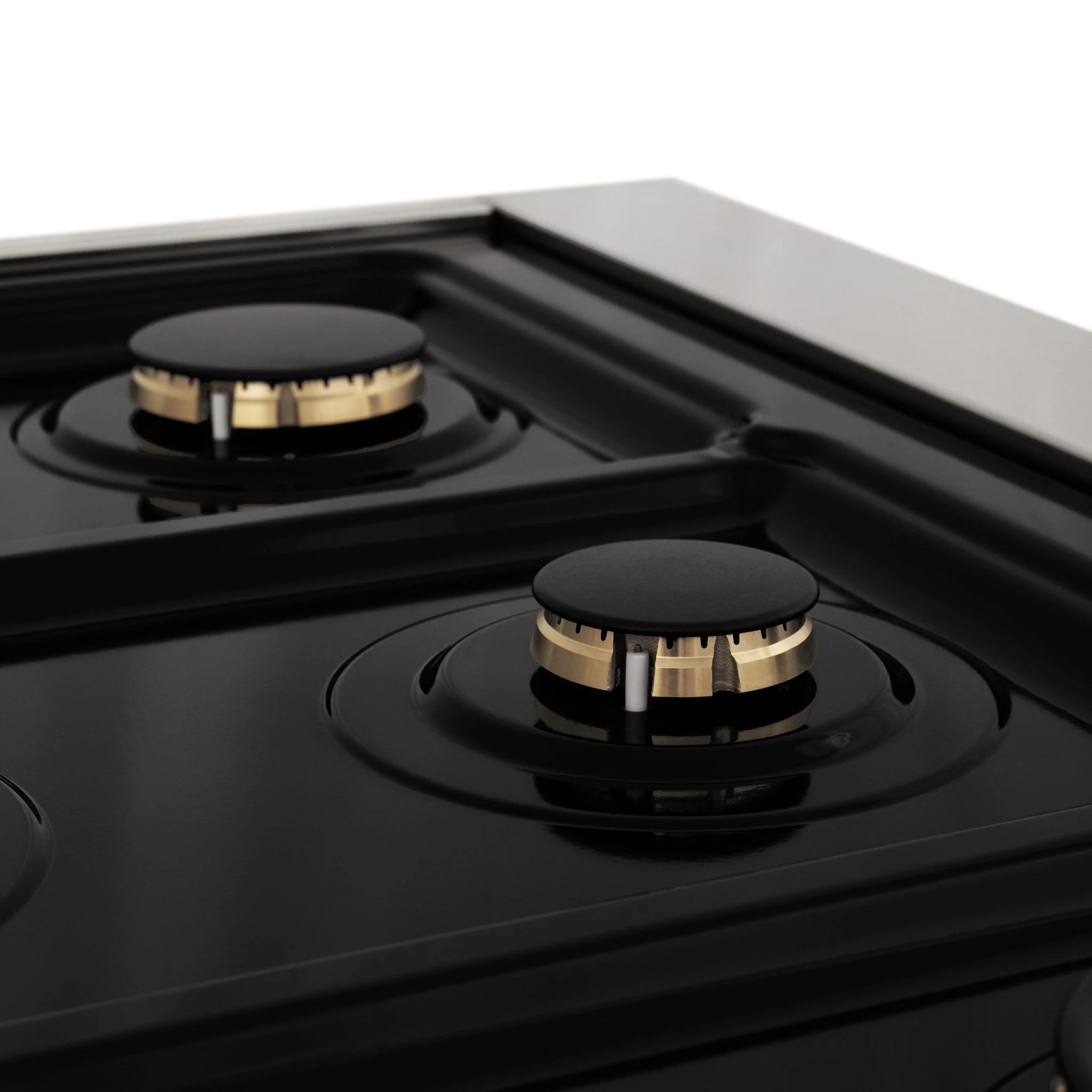 Dual fuel range cooktop with black burners and brass-toned burner caps, side close-up