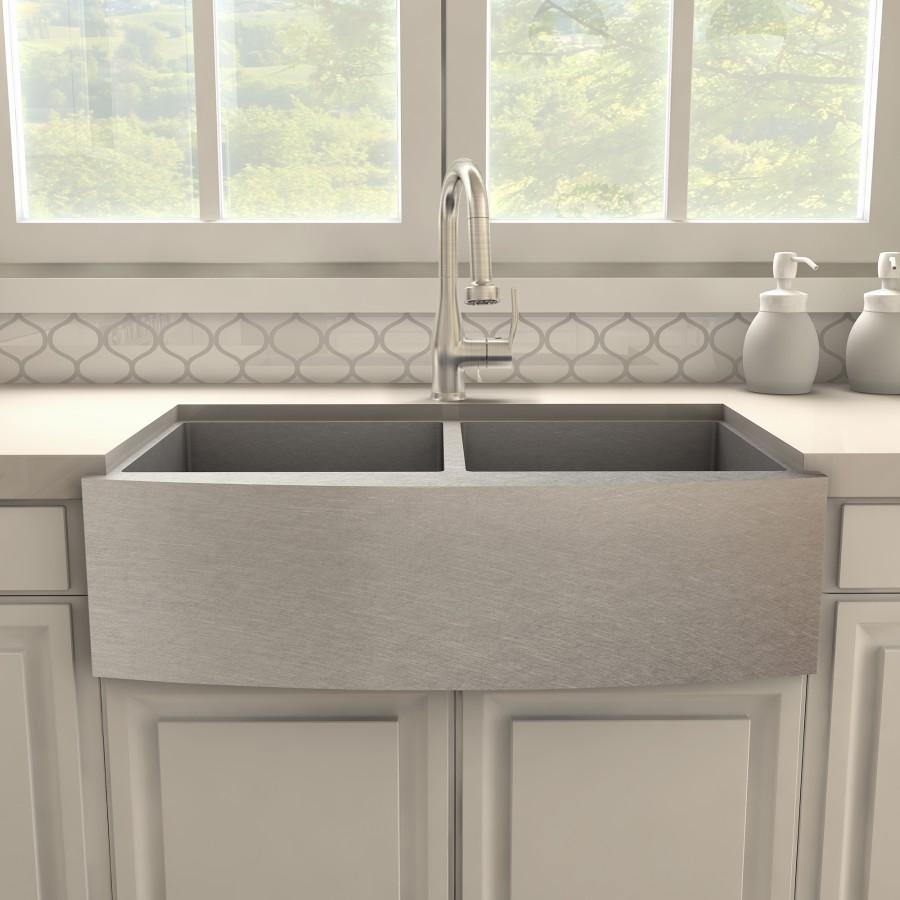 Brushed nickel kitchen faucet with curved spout on farmhouse-style sink