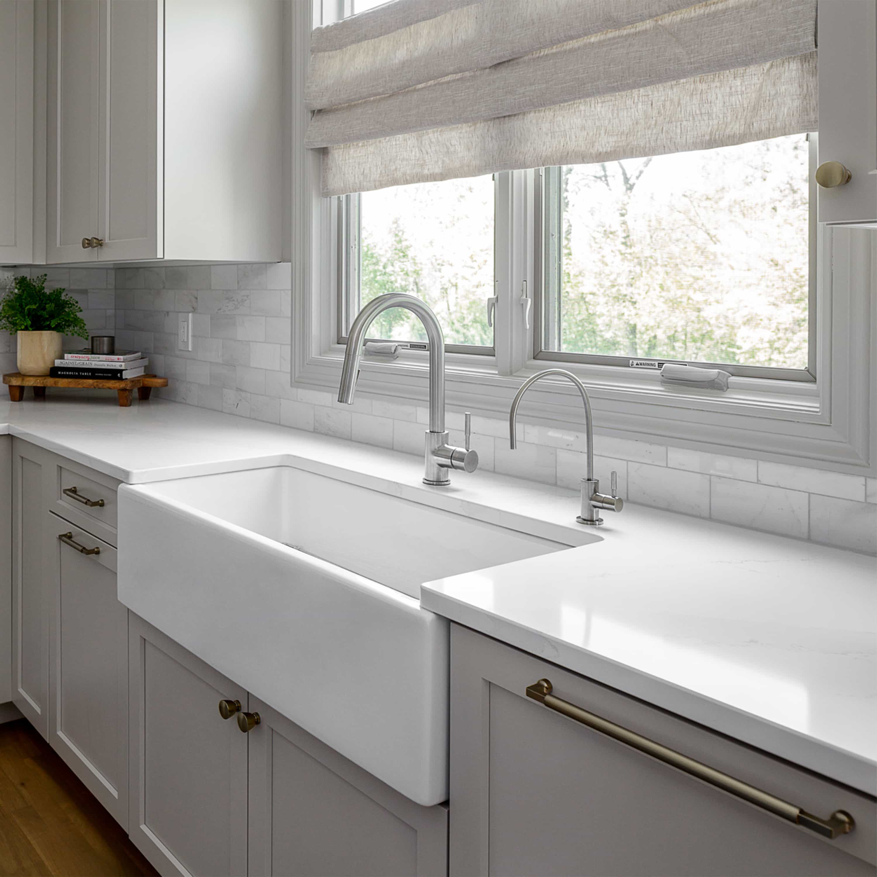 Chrome drink faucet with tall arched spout on white double sink.