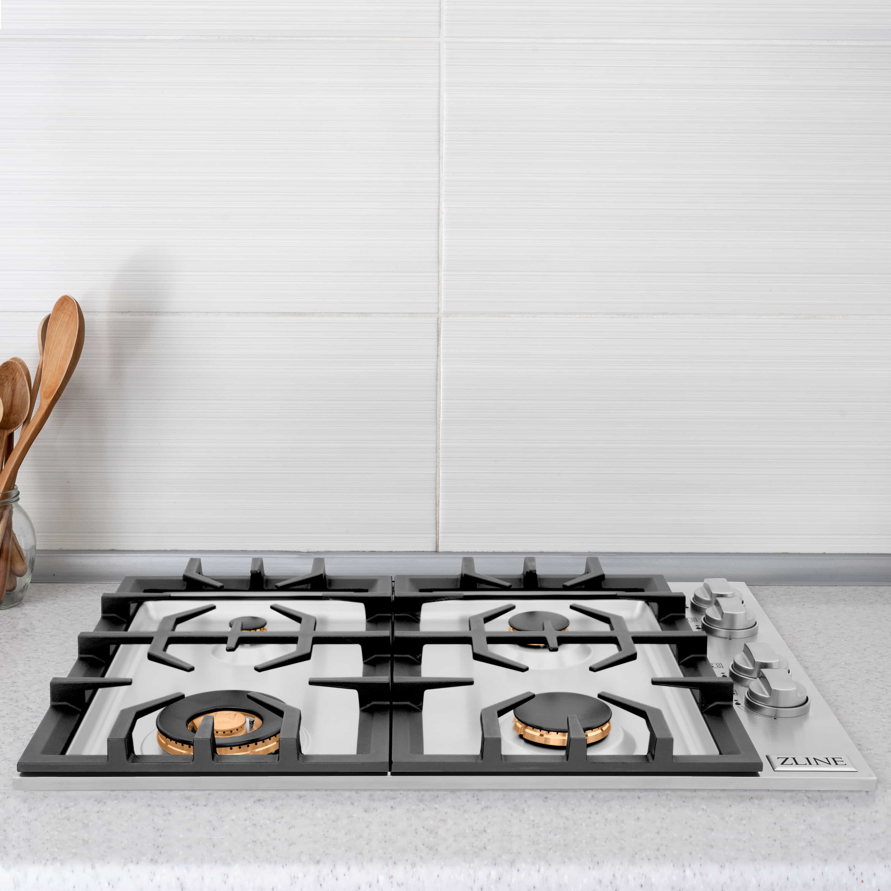 Gas cooktop top with cast-iron grates and brass burner bases, front close-up