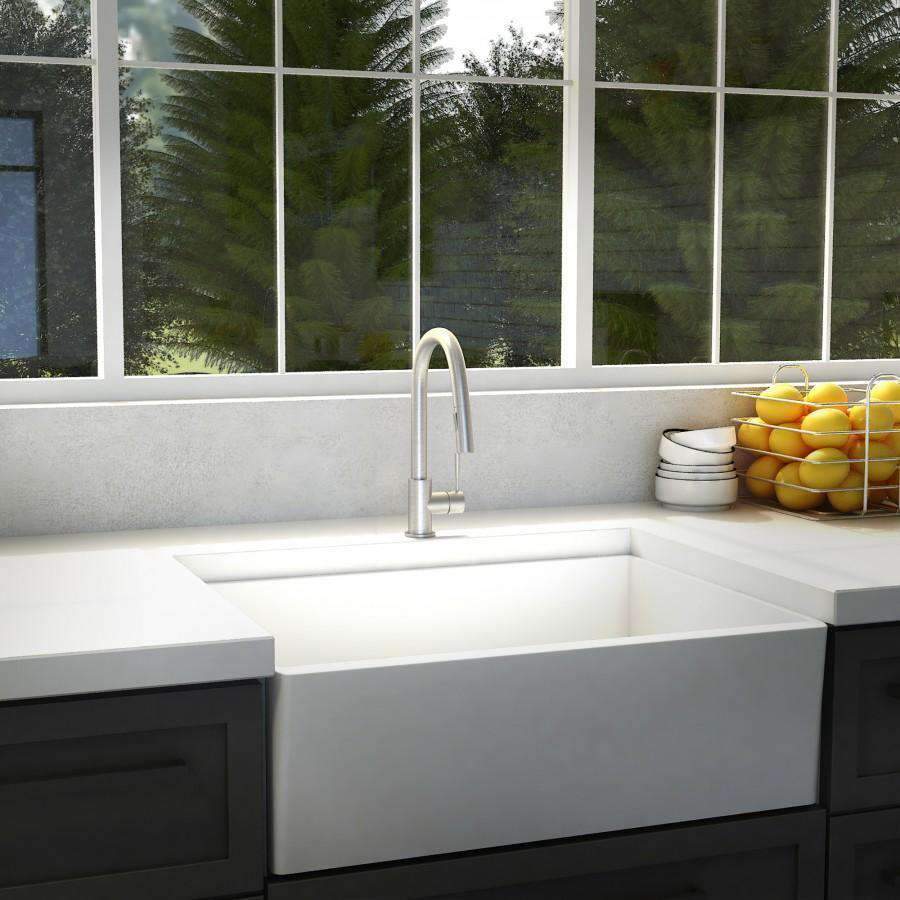 Brushed nickel kitchen faucet with tall curved spout above white sink basin