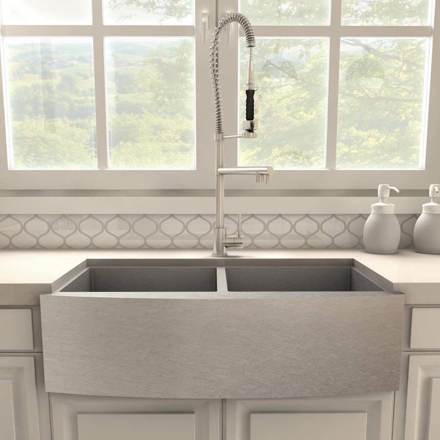 Brushed nickel kitchen faucet over double-basin sink with coiled hose and lever