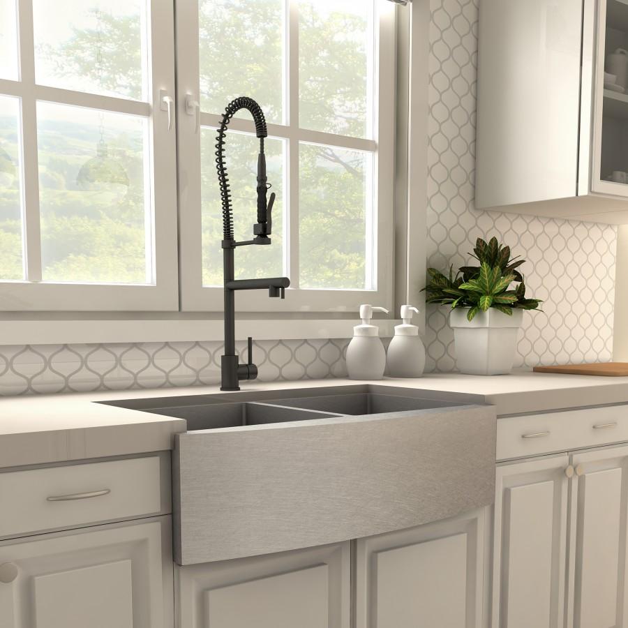 Matte black kitchen faucet over double-basin sink with pull-down sprayer.