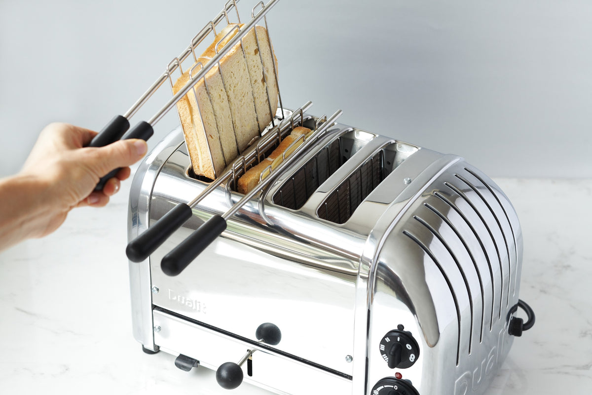 Chrome sandwich toaster with open rack and hand placing toast onto the grilling tray