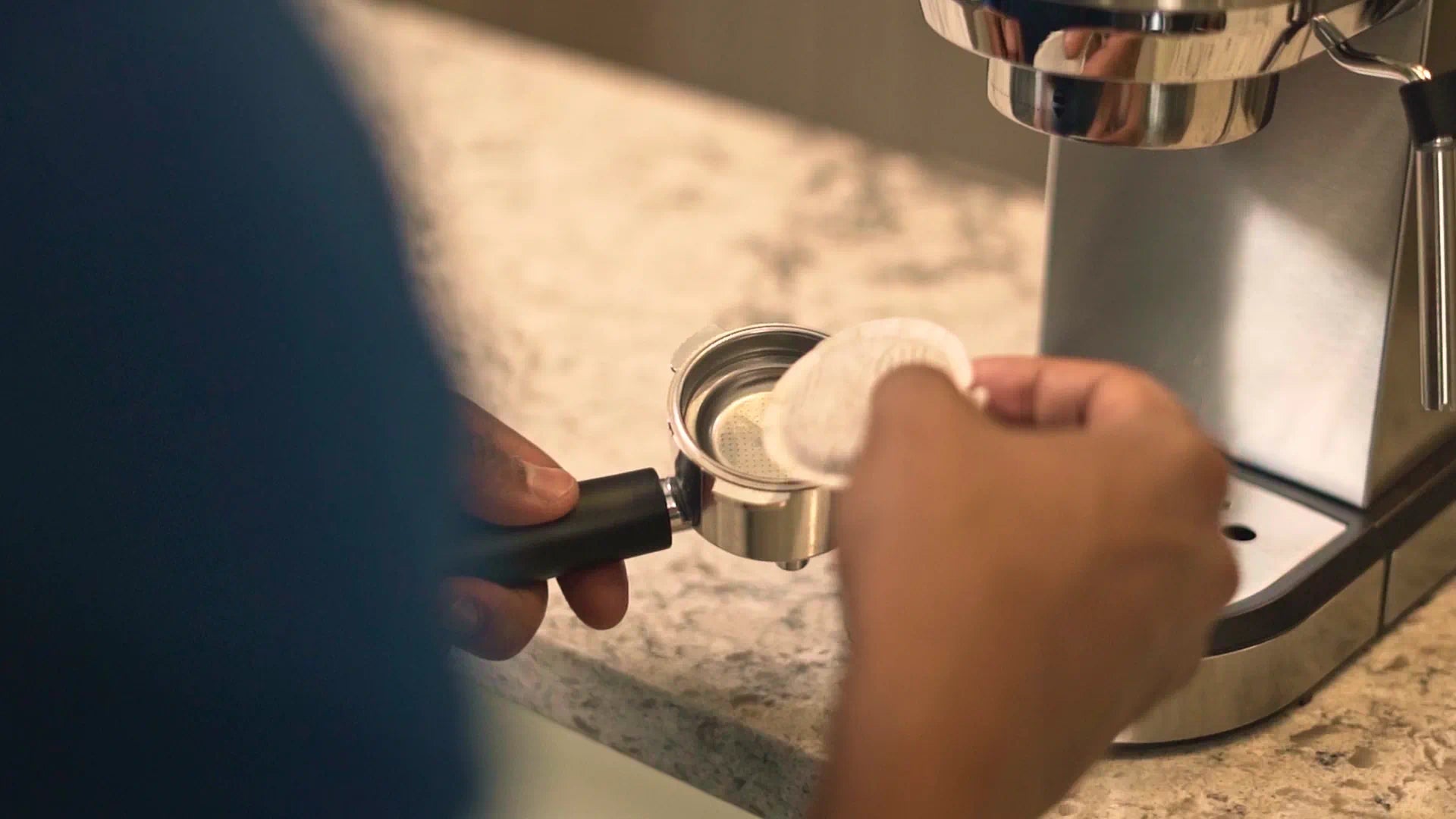 Hand inserting portafilter into espresso machine group head under the spout